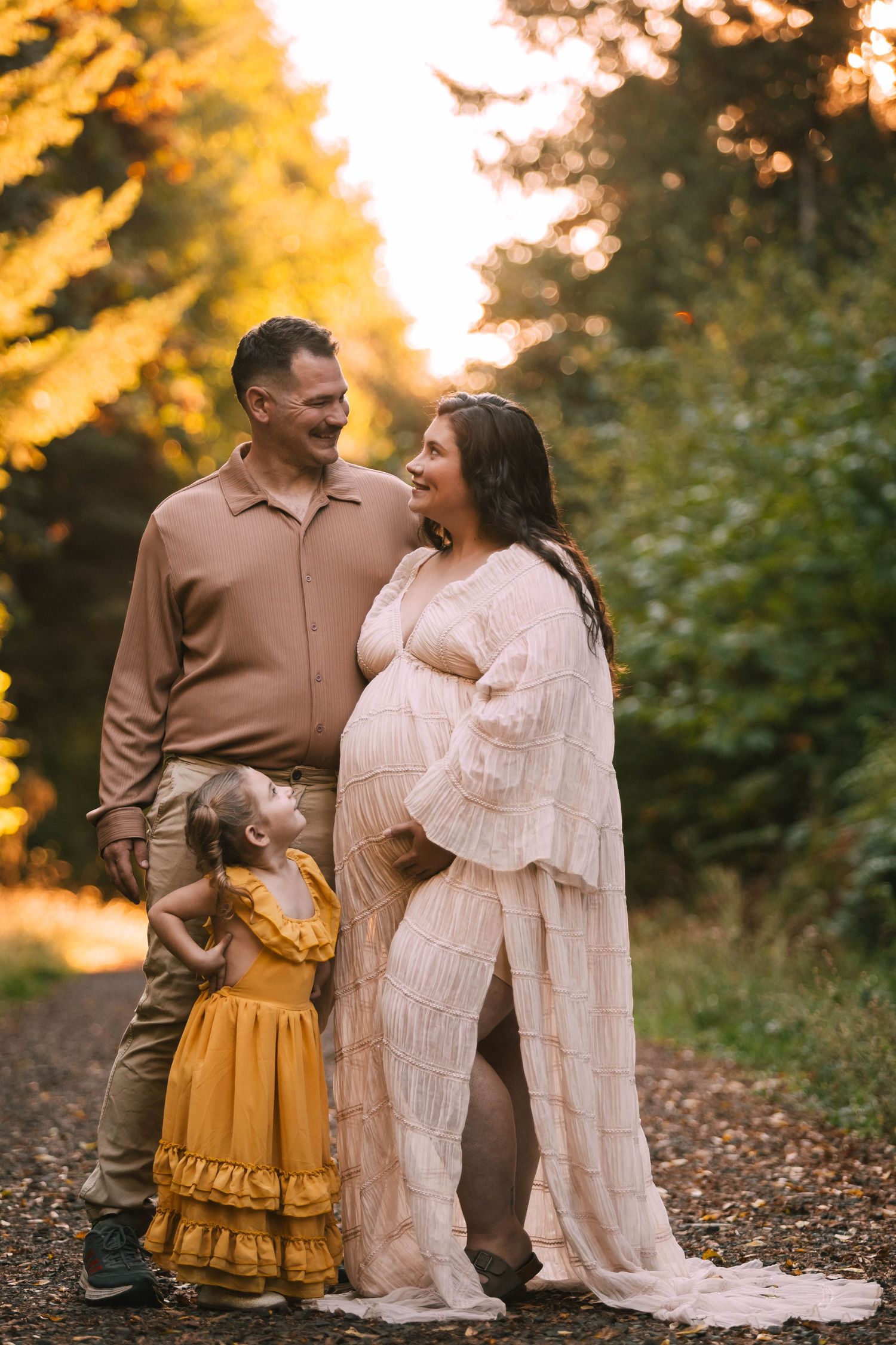 A couple shares intimate moments in a golden autumn forest setting wearing brown and cream colored outfits.