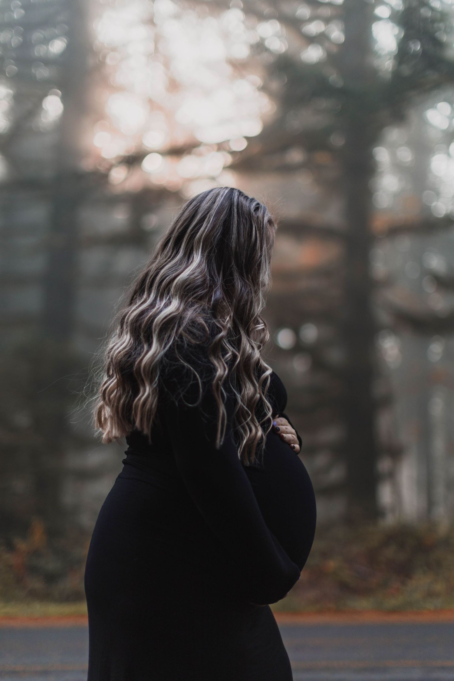 A series of four moody photos showing a person in a black sweater with long dark hair against a blurred forest background.
