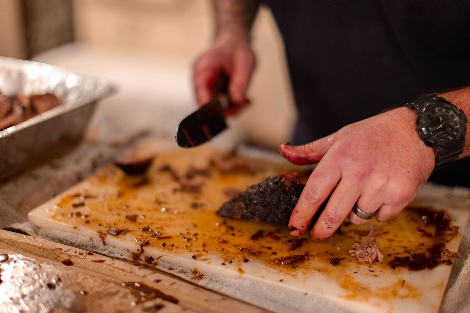 Hands chopping and preparing ingredients on a wooden cutting board in a kitchen setting.