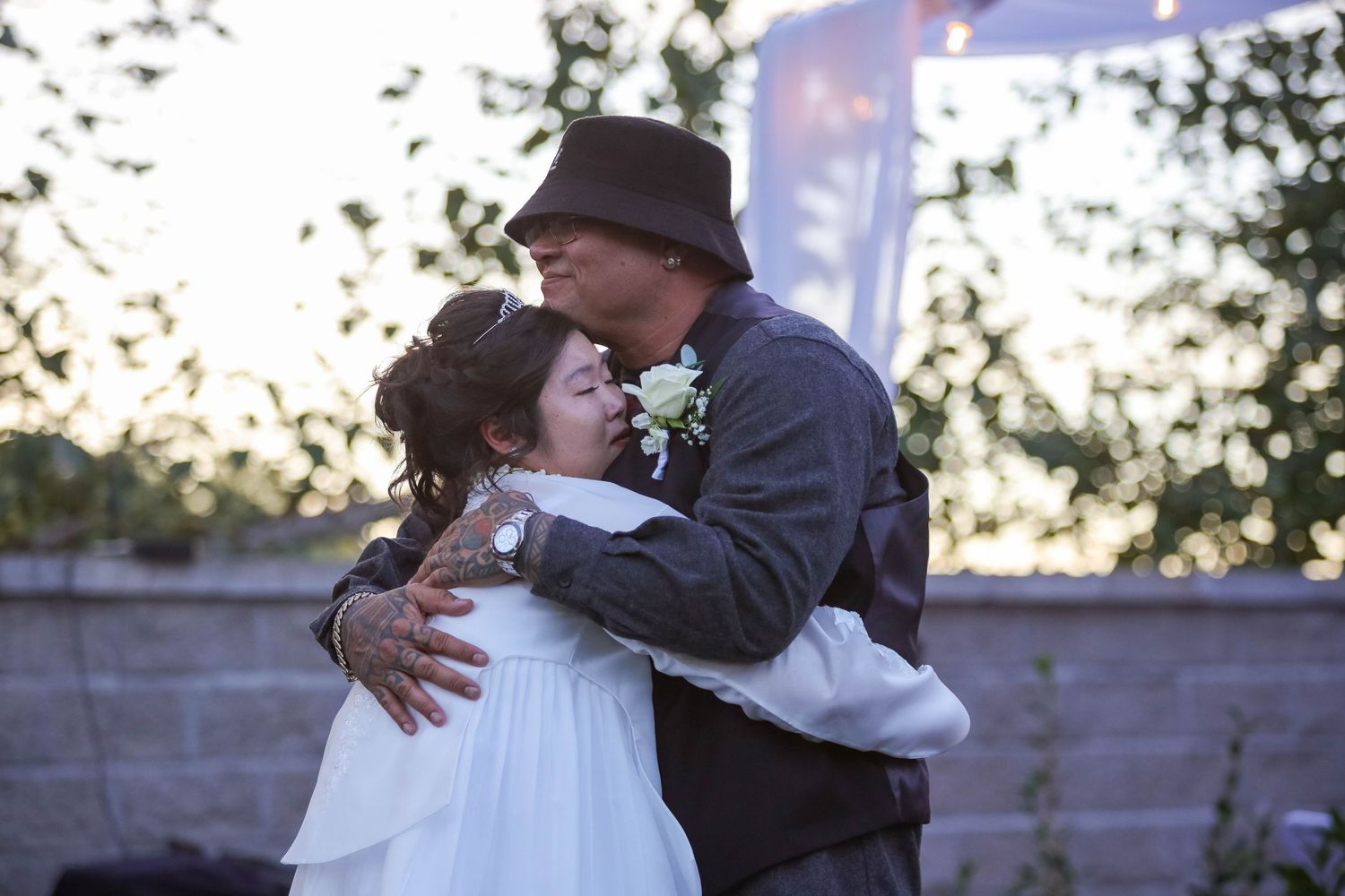 People sharing warm hugs and embraces at an outdoor event with trees in the background.