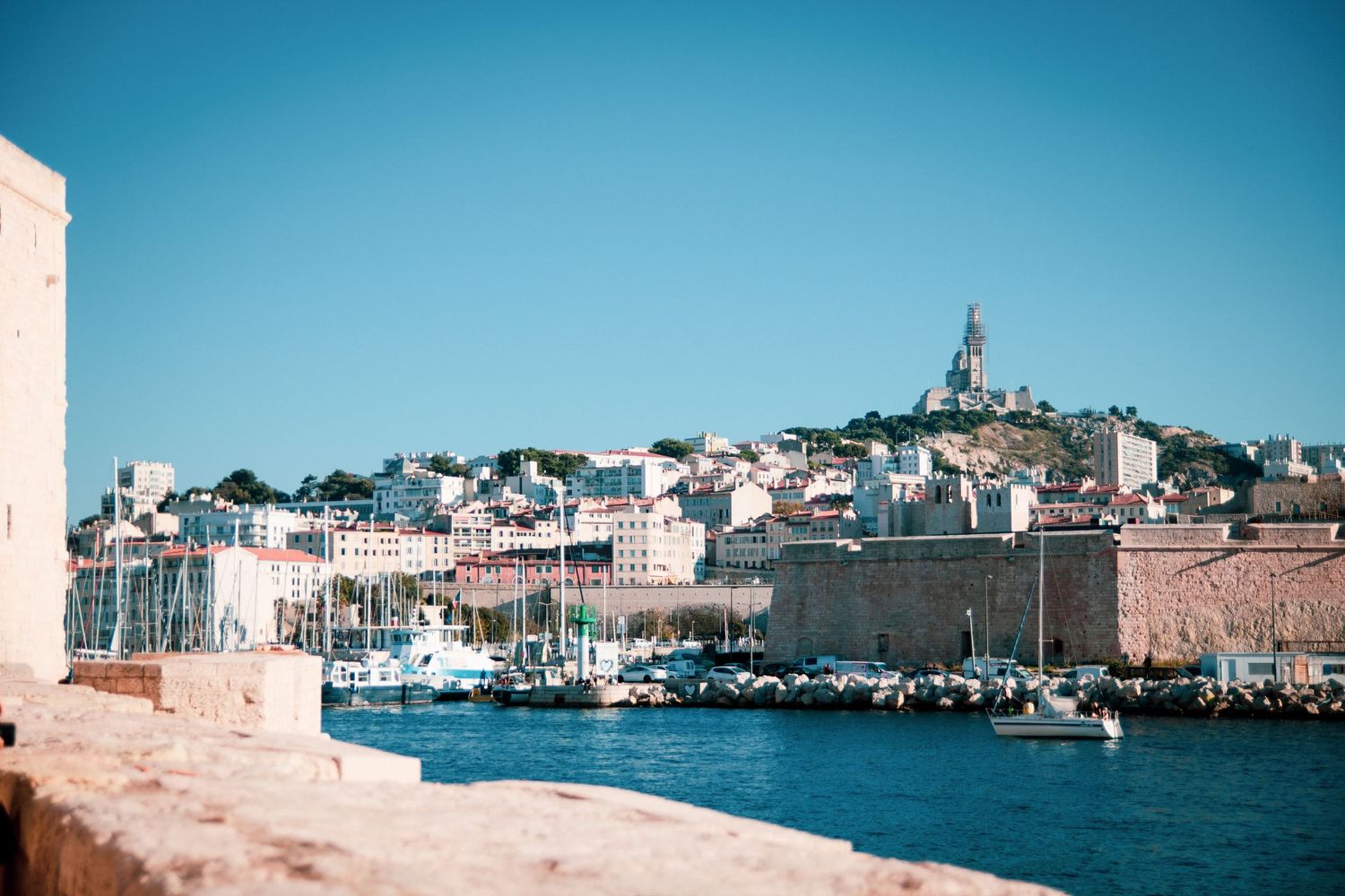 Vue panoramique du Vieux-Port de Marseille avec la basilique Notre-Dame de la Garde en arrière-plan, ambiance ensoleillée et méditerranéenne