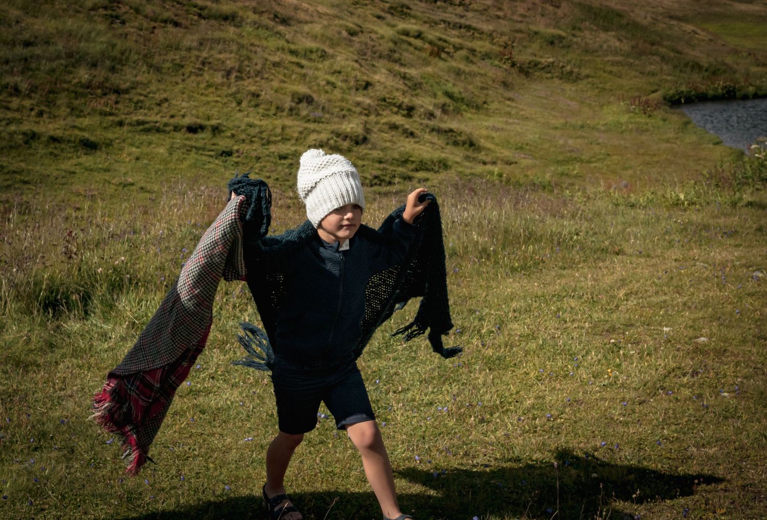 Enfant joyeux tenant une veste de marié en extérieur, ambiance naturelle et spontanée lors d'un mariage en plein air, moment plein de vie
