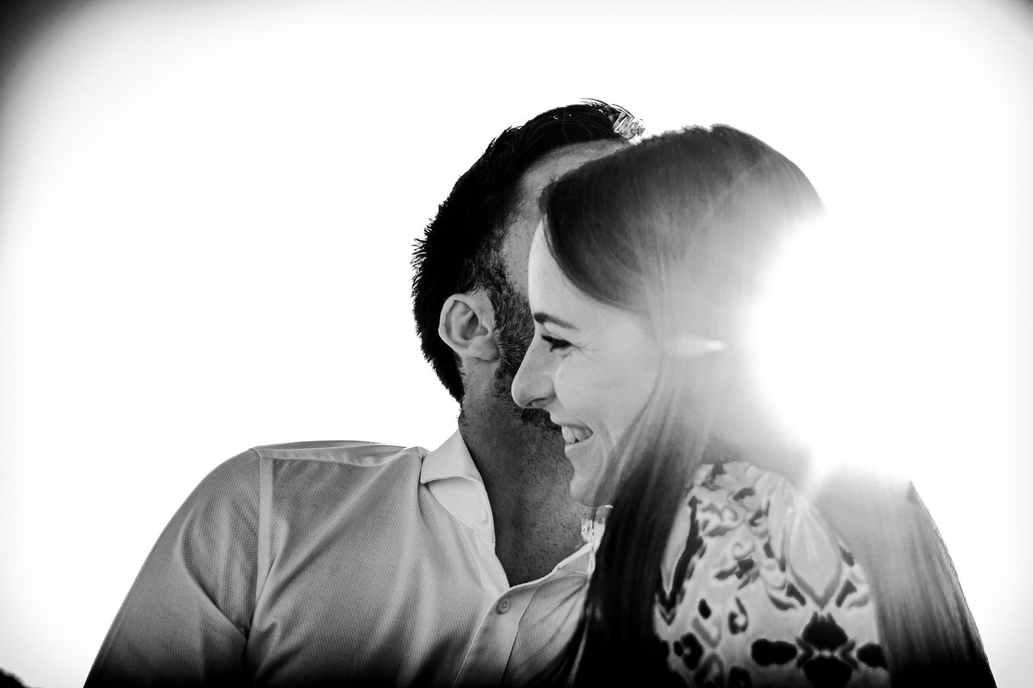 Photo couple en noir et blanc, joachim dit quelque chose à l'oreille d'Amélie qui rigole devant un soleil éblouissant avec Flare
