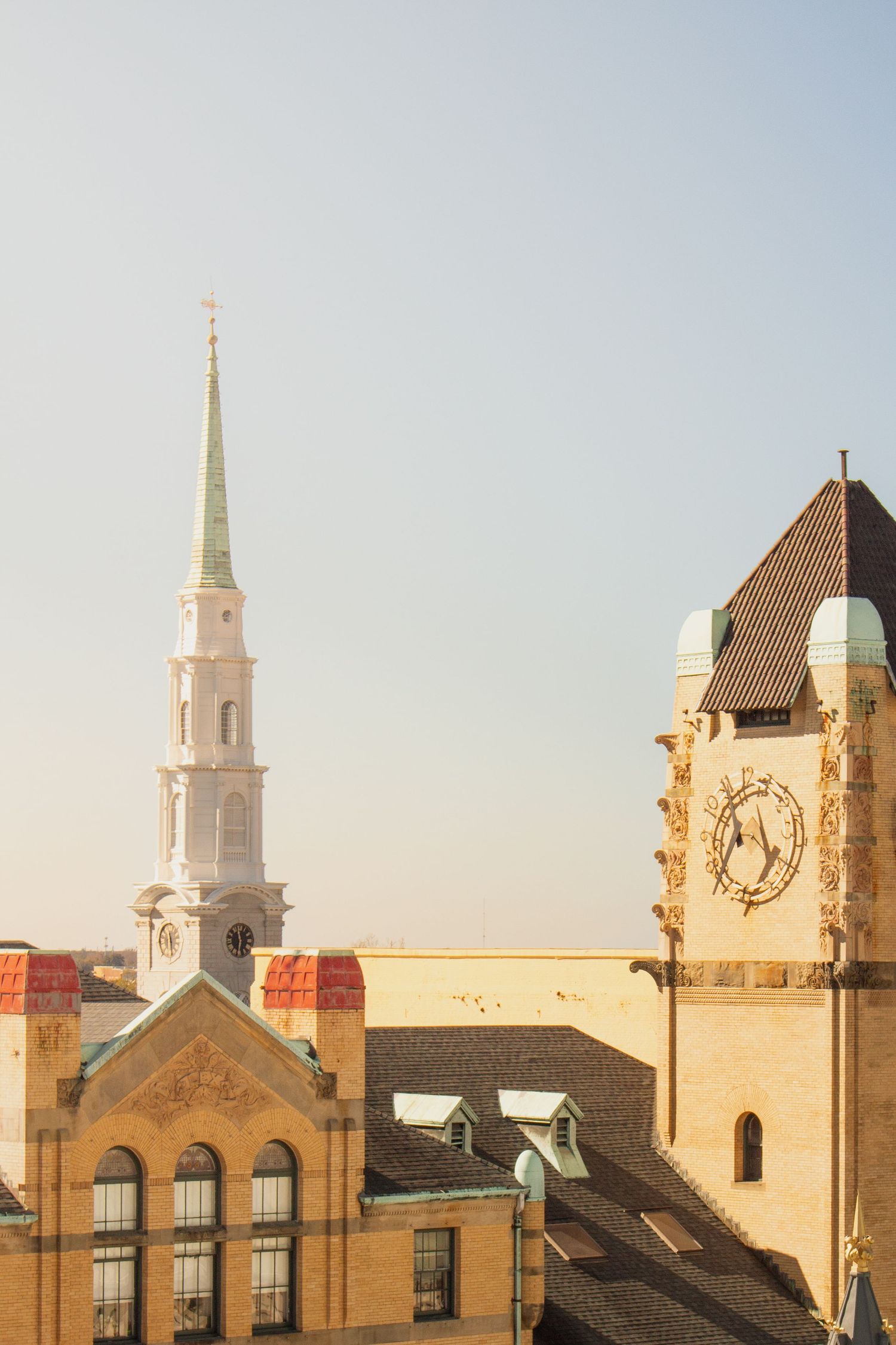 Historic church spires and clock towers rise against a pale sky in a classic New England cityscape. Savannah Georgia.