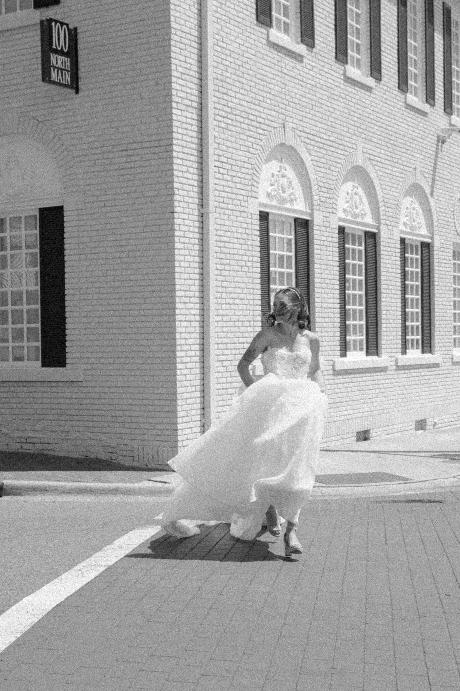 Bride walking through a quiet city street on her wedding day in a flowing white dress.