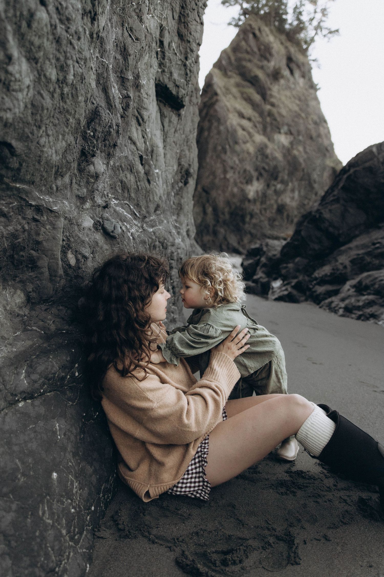 A mother kisses her daughter affectionately at an outdoor documentary family photoshoot