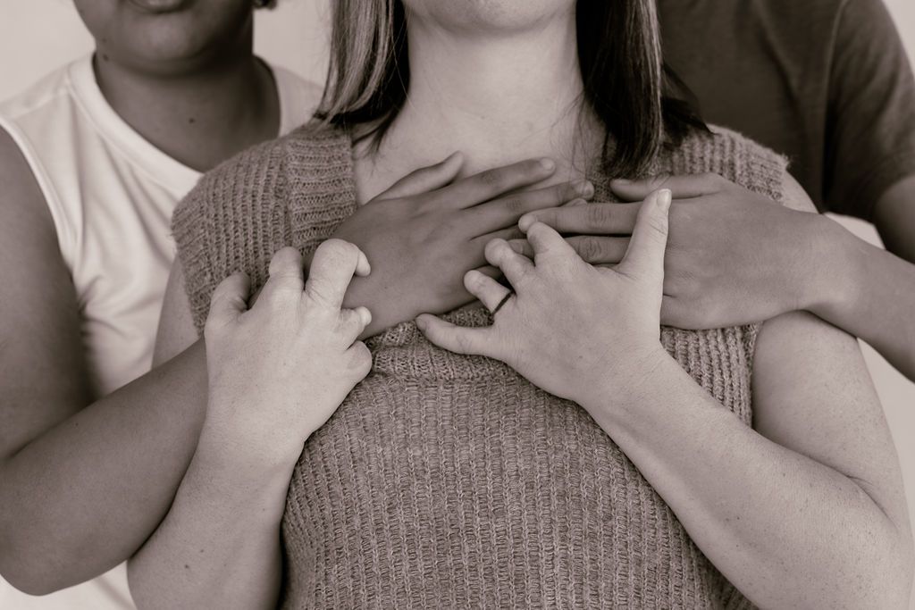 A mom's hands intertwined with her two children's hands