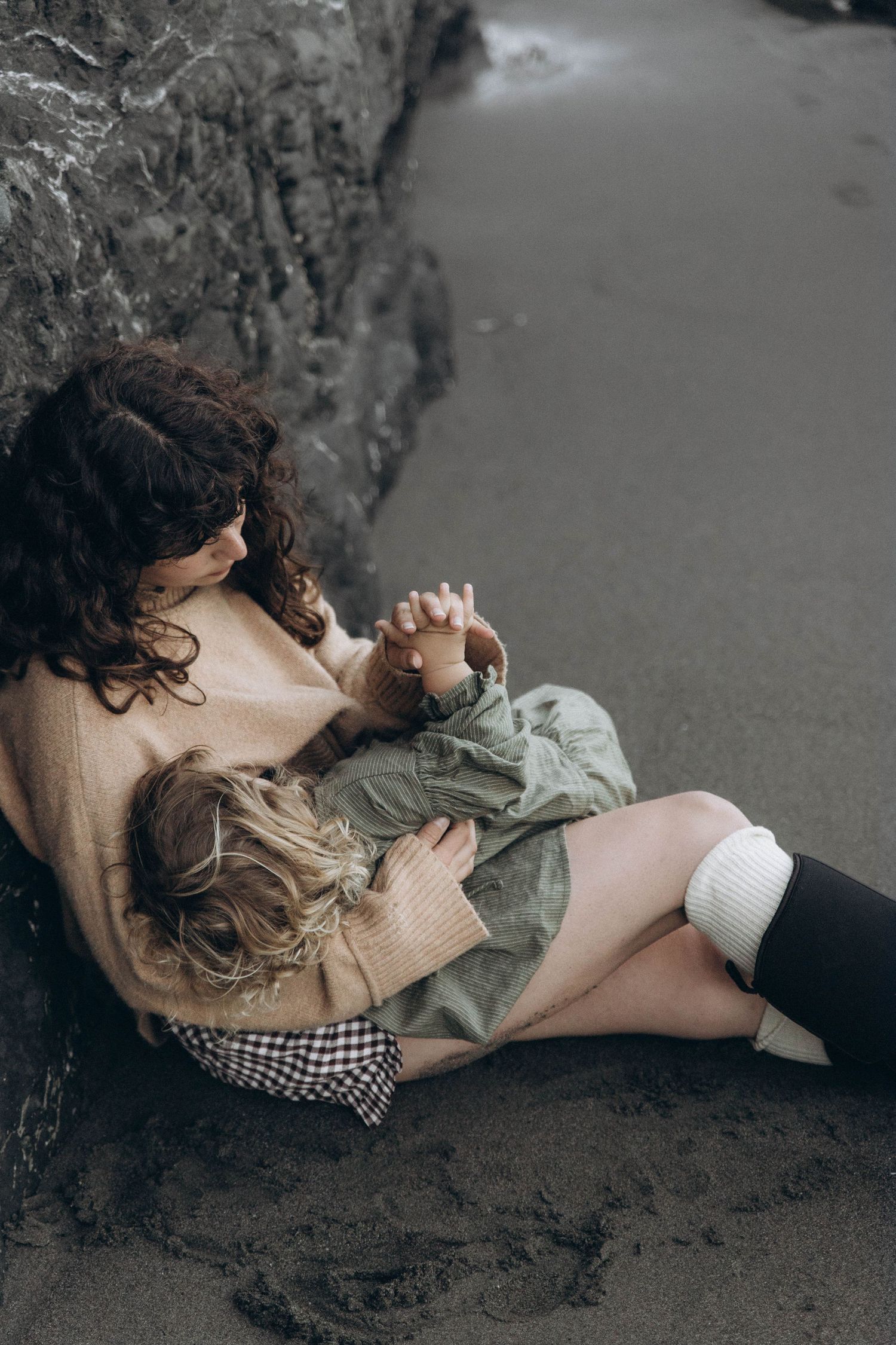 A mother cuddling her baby on the beach during a sunrise photoshoot