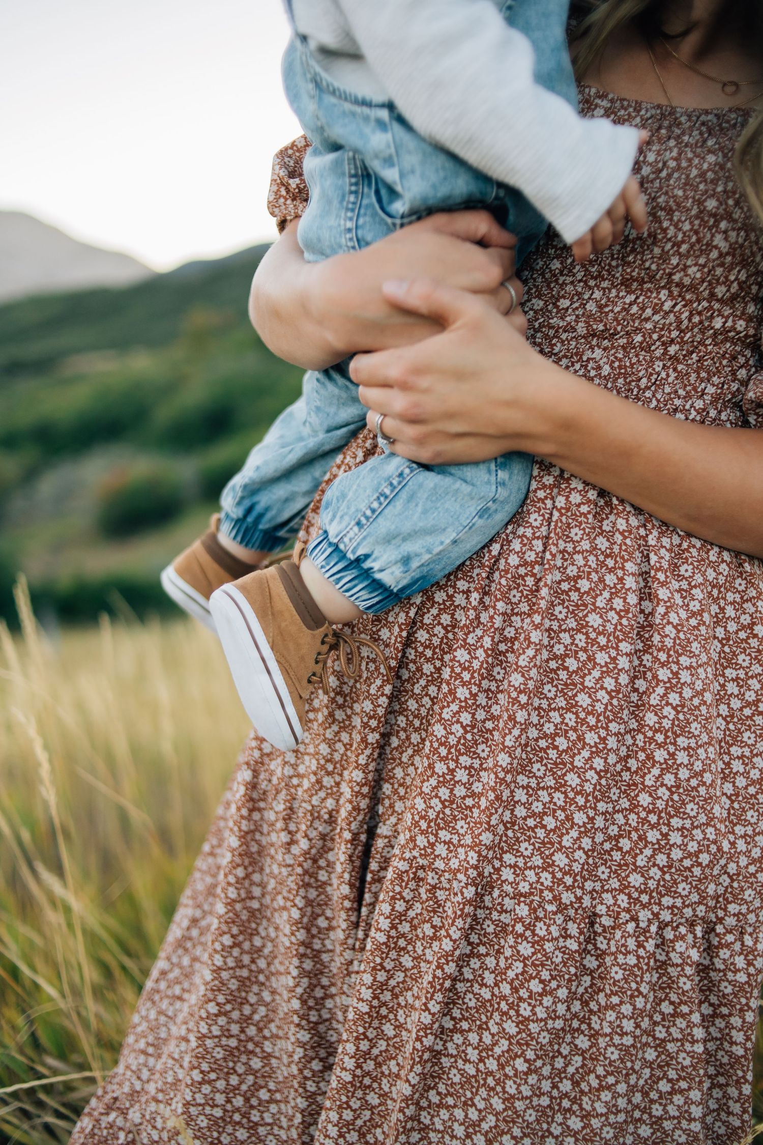 Details of a baby's shoes and a mom's hands holding her baby during a family candid photoshoot