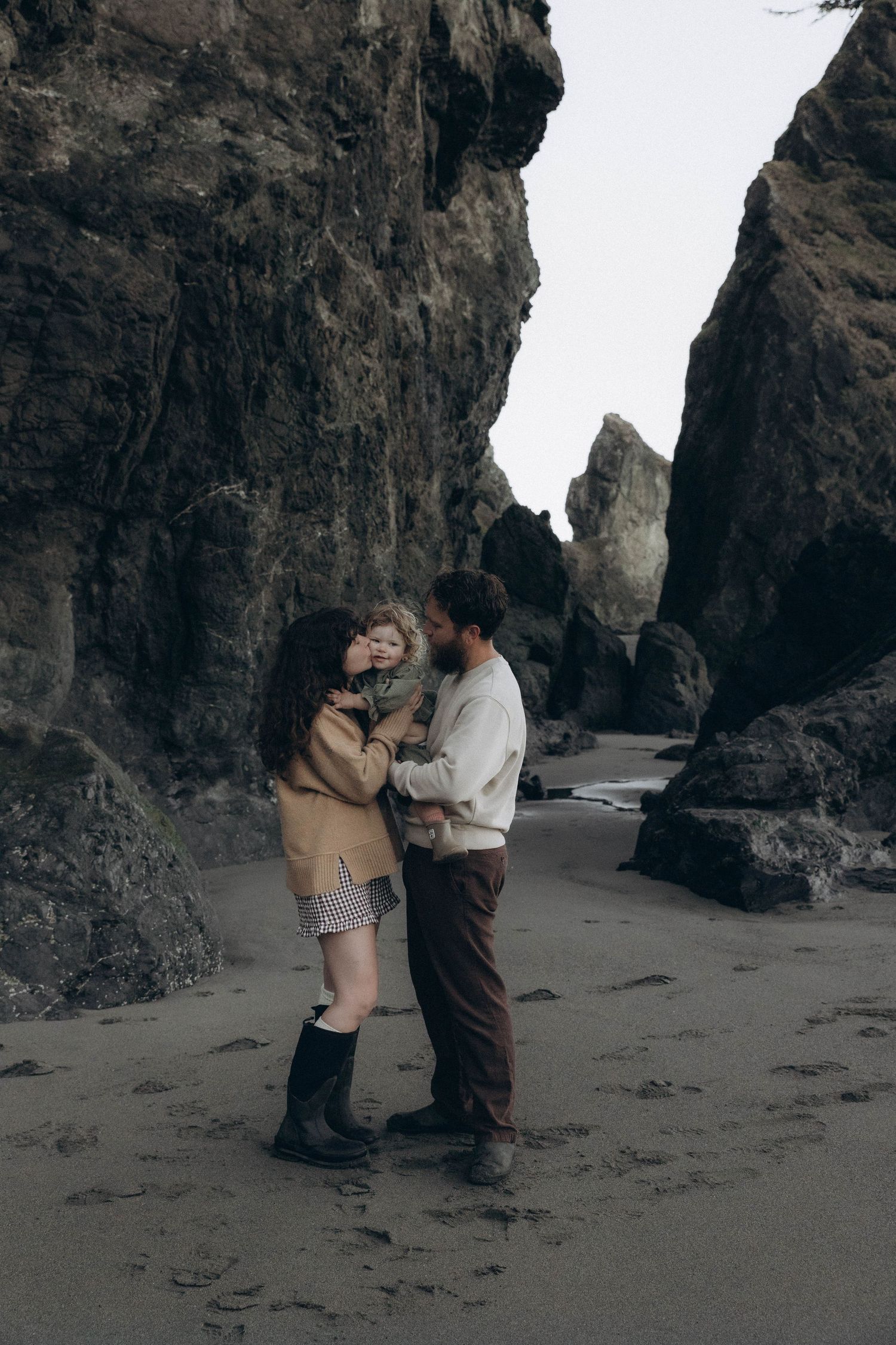 A mom and dad cuddling their little girl during a documentary photoshoot at sunrise