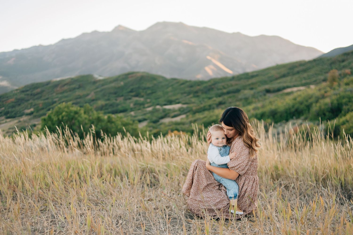 A mother embracing her baby in the mountains at golden hour