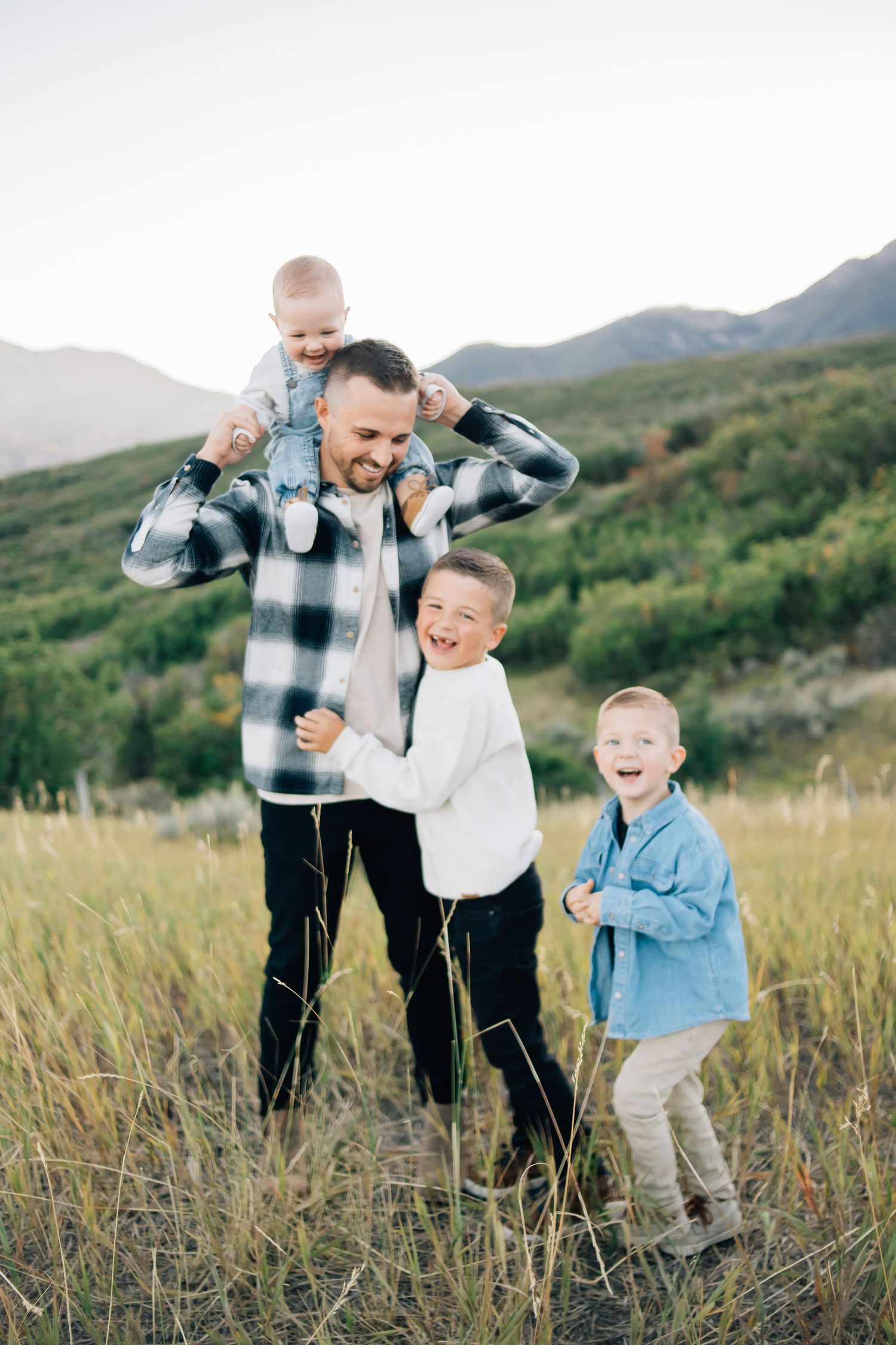 A dad with his sons playing in the Utah mountains at golden hour
