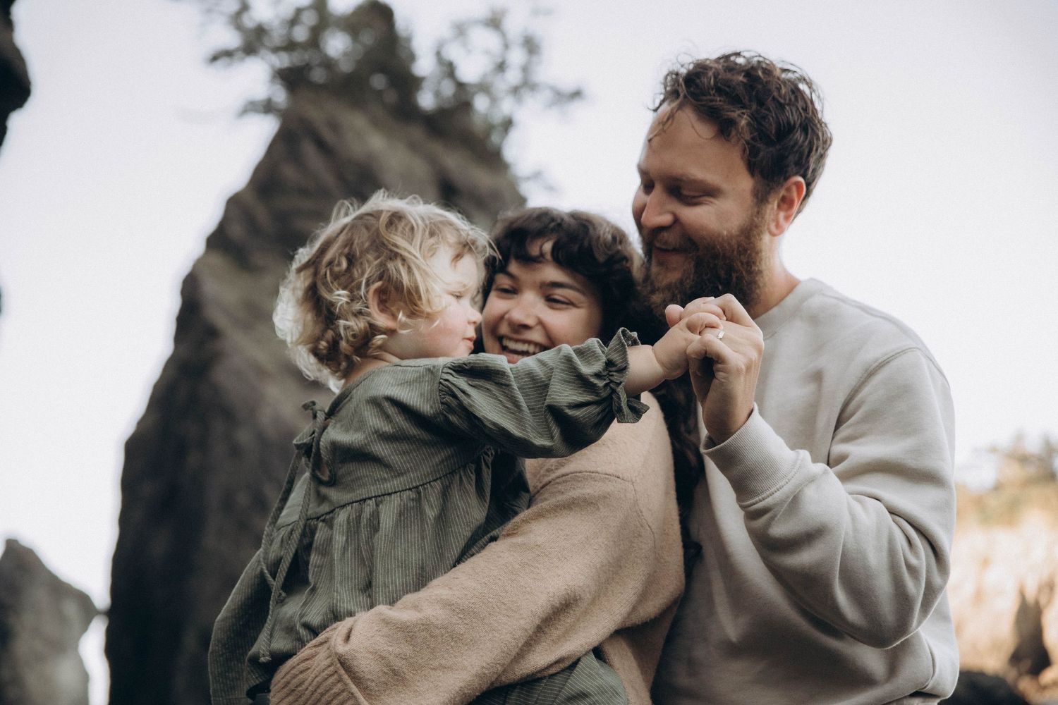 A family of three interacting joyfully during a documentary photoshoot at sunrise on the beach