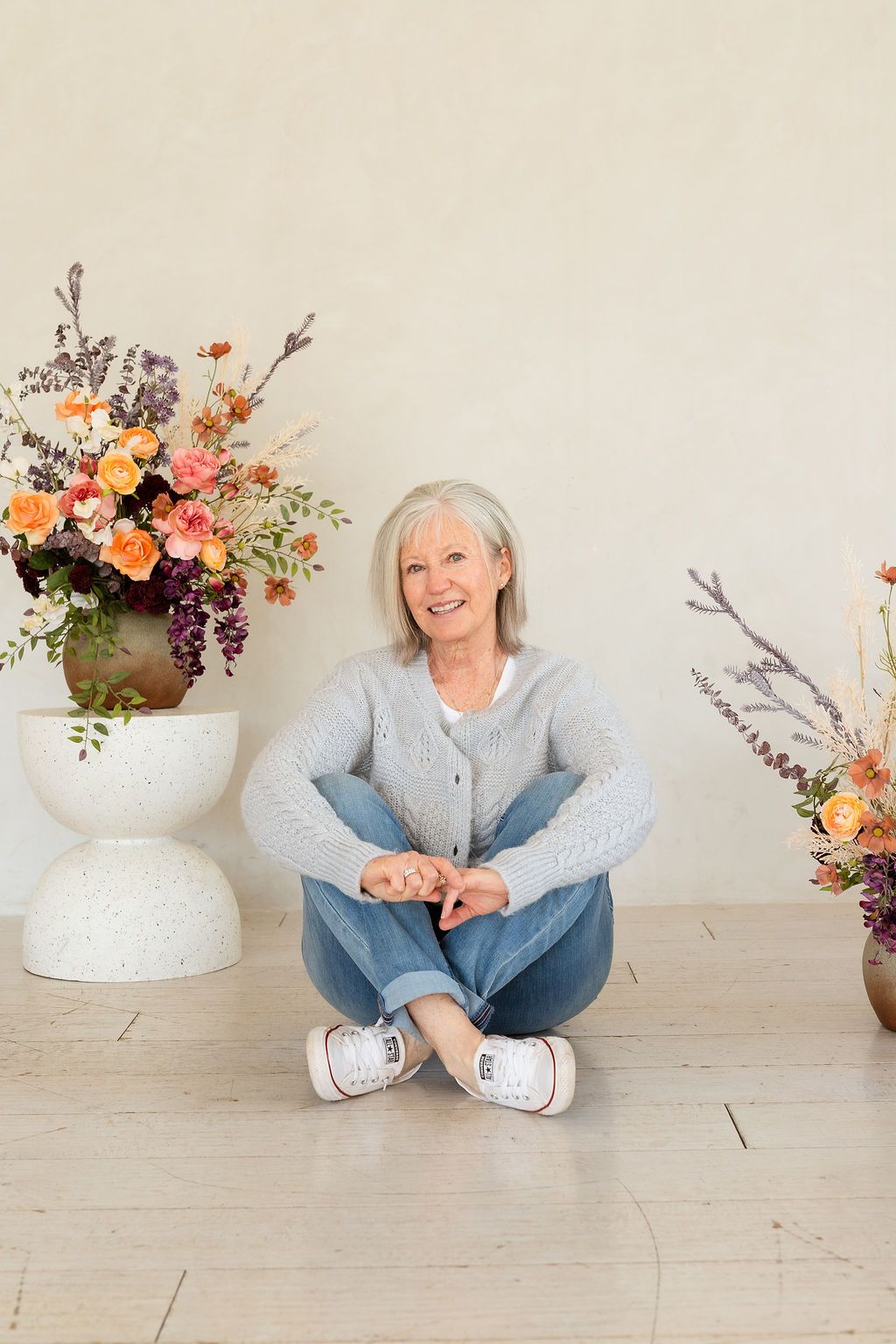 Portrait of a grandmother in white studio with flowers during a photoshoot celebrating women