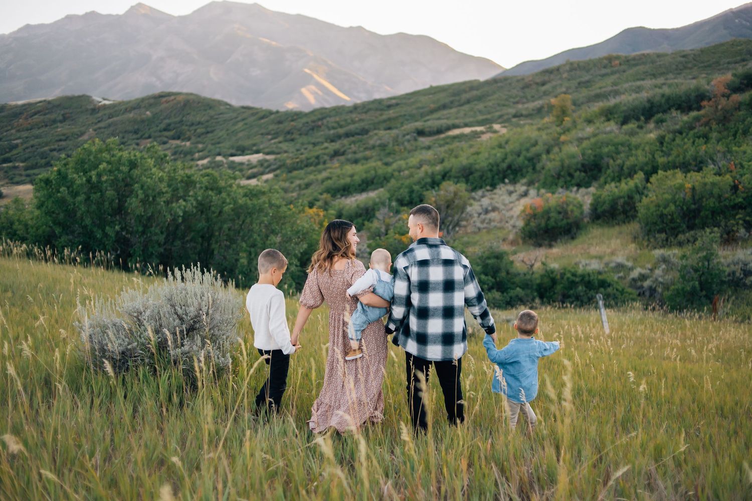 A family walking into the sunset during a golden hour family photo session in the mountains of Northern Utah
