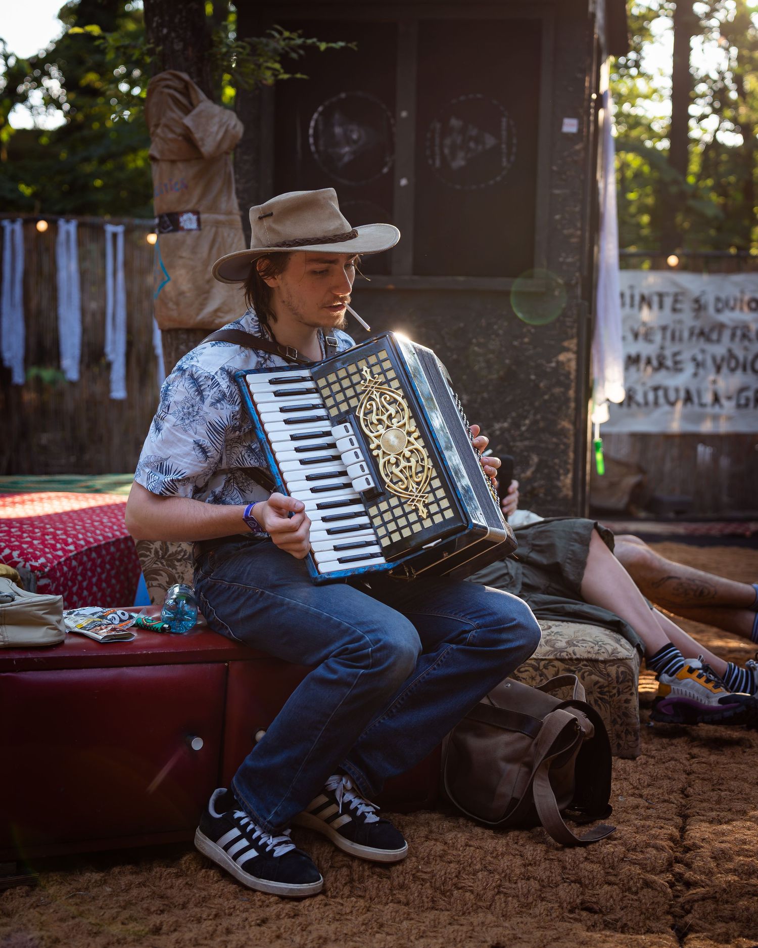 Muzician cu palarie cantand la acordeon stand pe o valiza la un festival