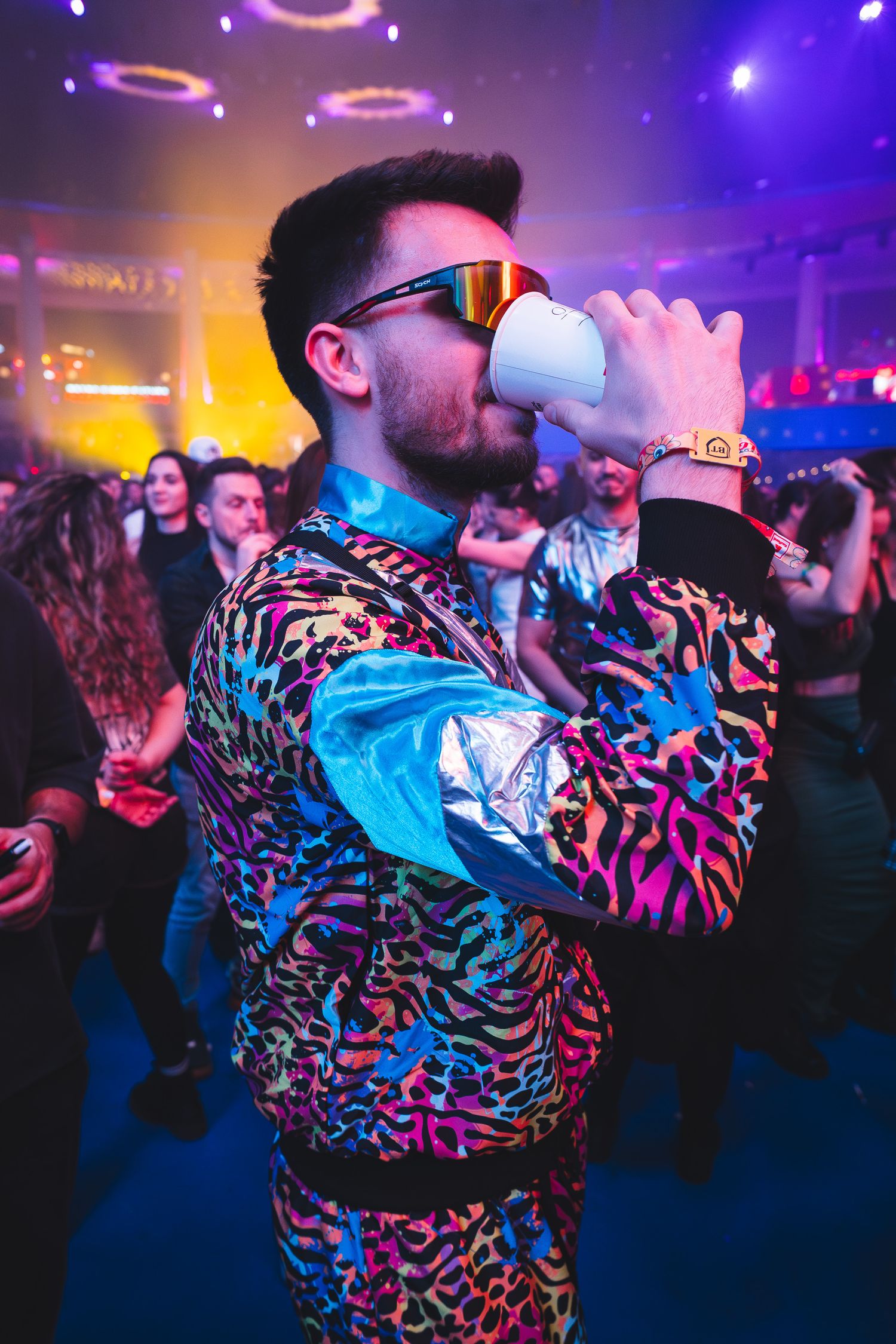 Barbat cu ochelari de soare distrandu-se si band un cocktail la un eveniment de noapte