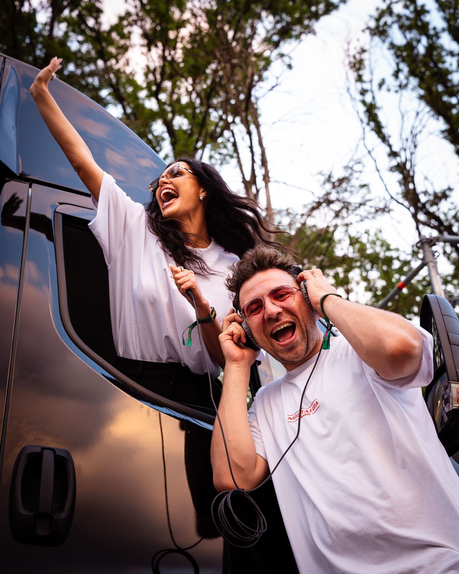 Tanar cu casti si o femeie distrandu-se intr-o masina la un festival in aer liber