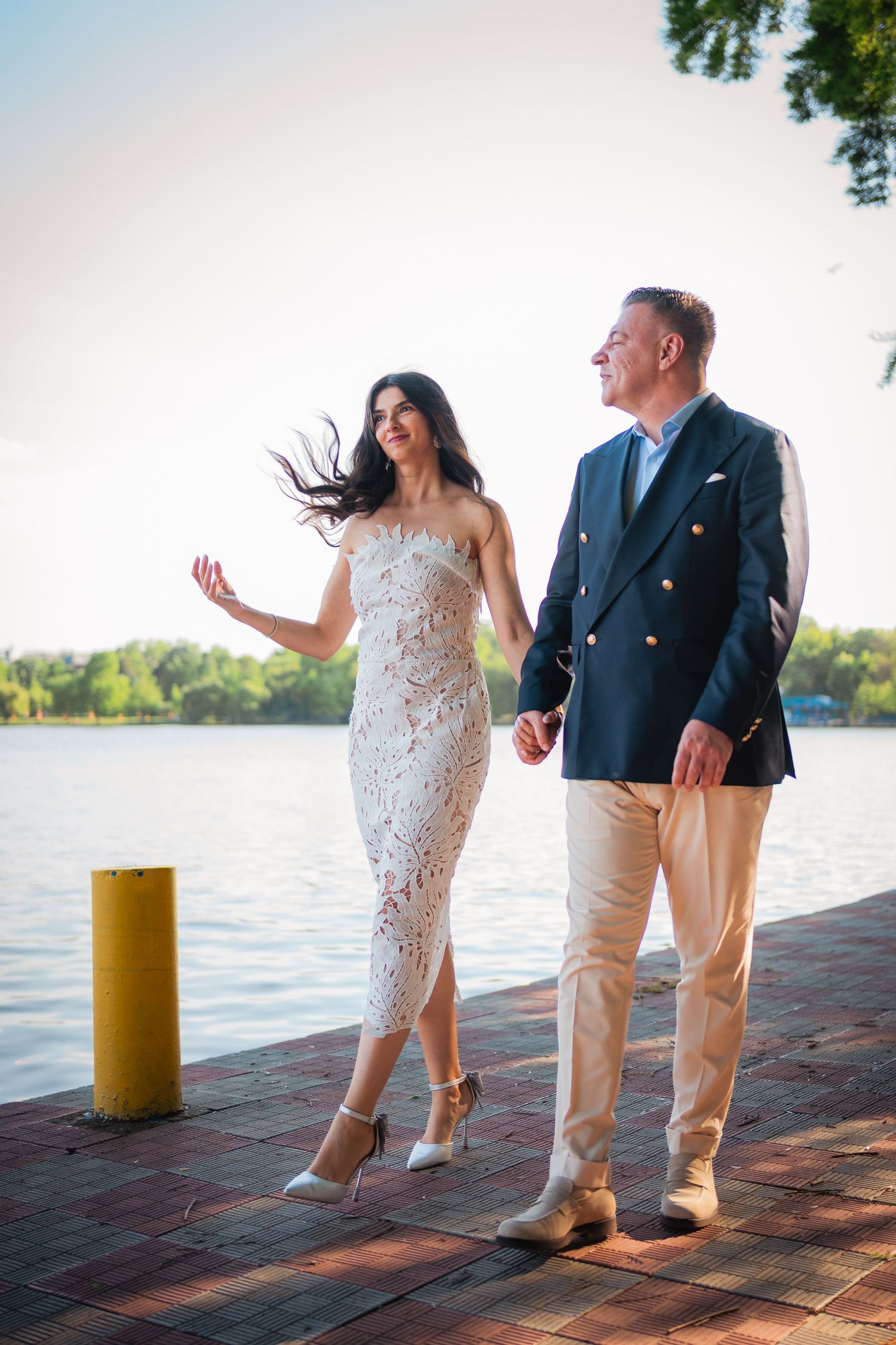 Mireasa eleganta in rochie alba si mire plimbandu-se pe un ponton la lac, fotografie de nunta