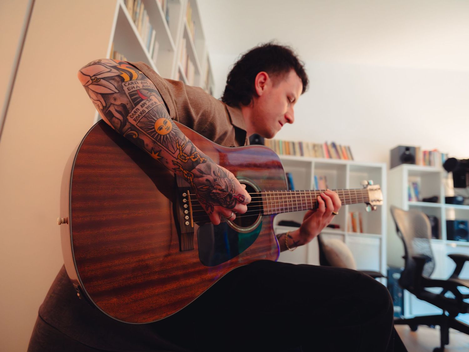 Muzician cantand la chitara acustica intr-un birou acasa, fotografie de portret artistic