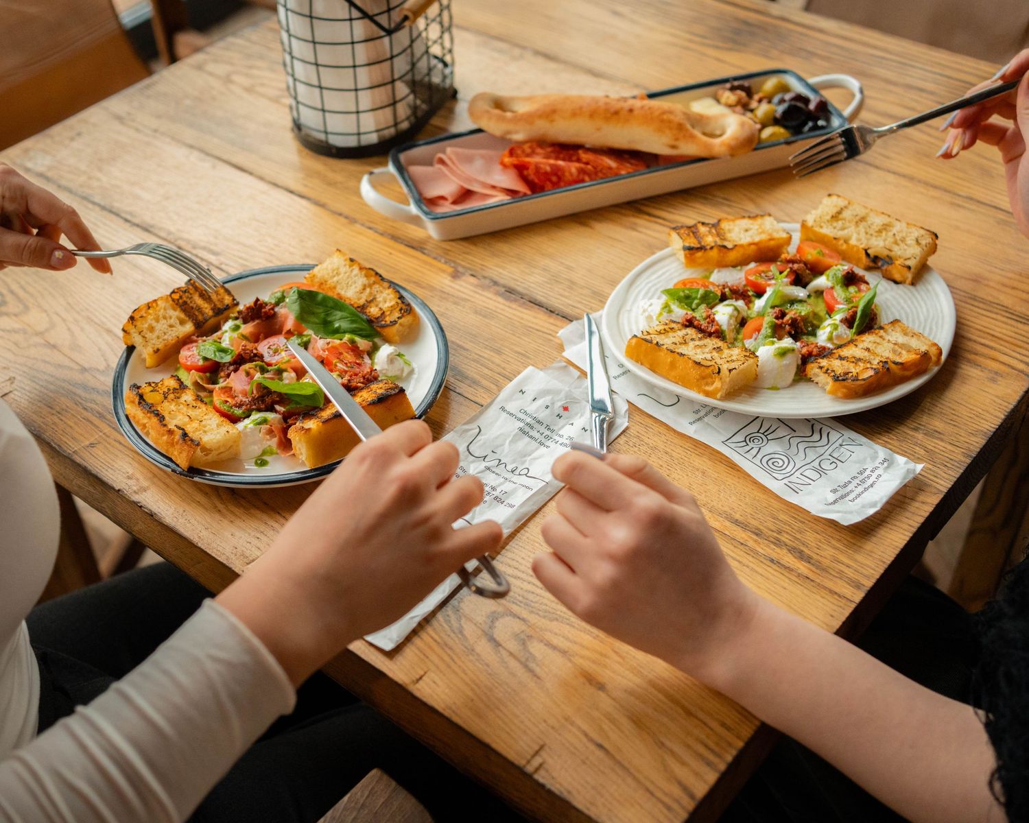 Doua persoane luand masa la un restaurant cu aperitive italiene, fotografie comerciala de lifestyle