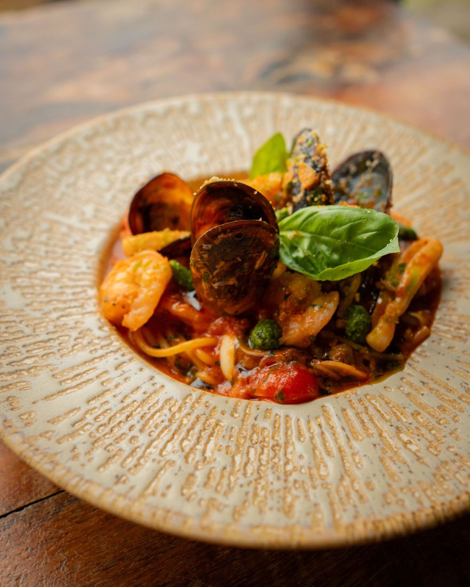 Paste cu fructe de mare si sos de rosii pe masa din lemn, fotografie comerciala culinara