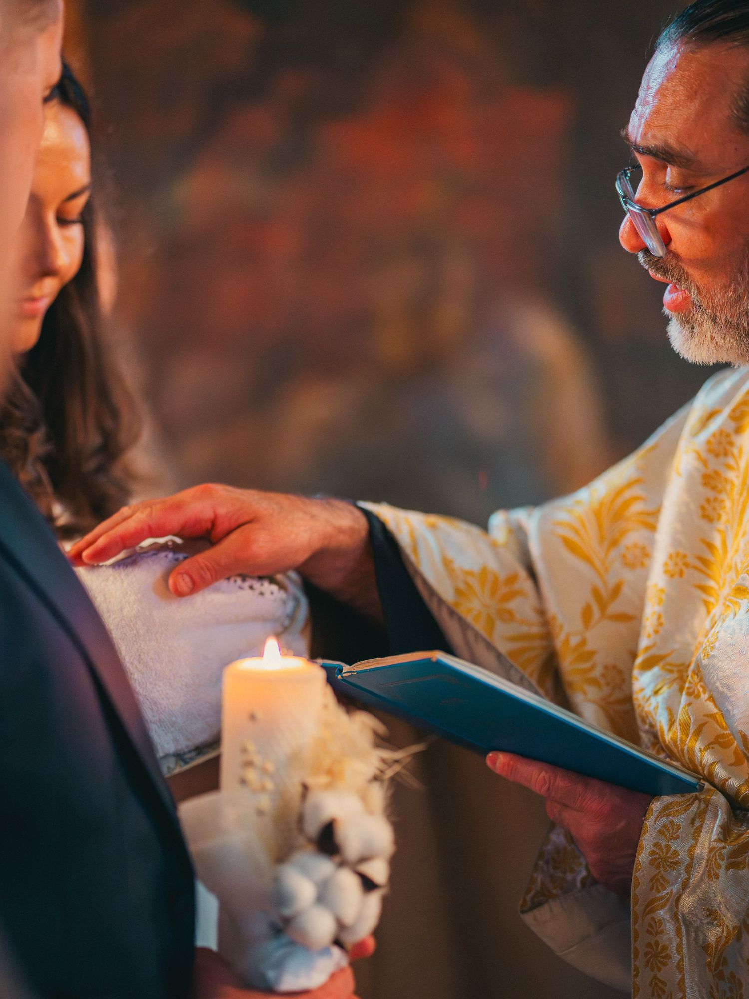 Preot ortodox oficiind ceremonia religioasa cu lumanare aprinsa, detalii slujba botez