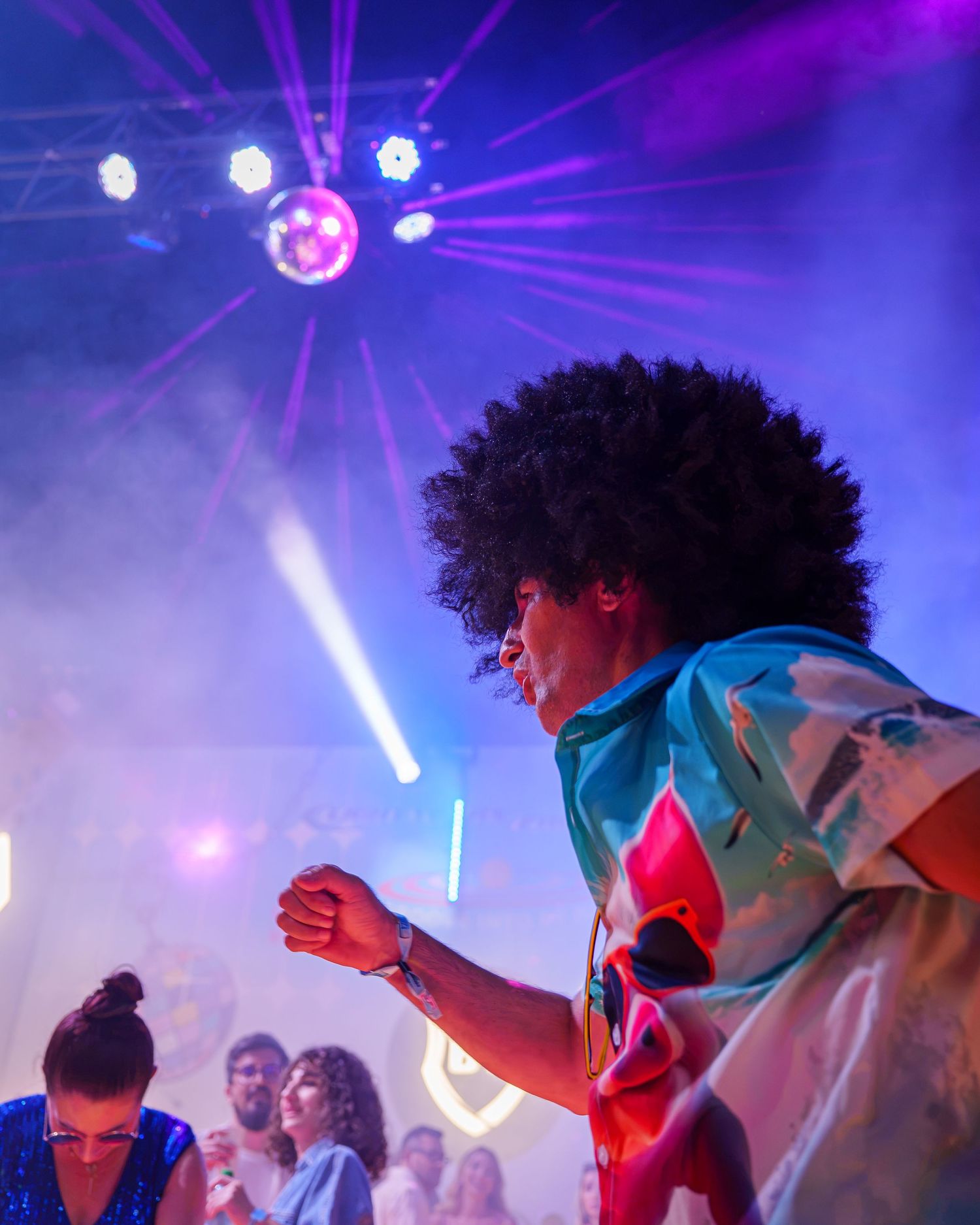 Persoana cu peruca afro dansand sub lumini disco si fum la o petrecere tematica