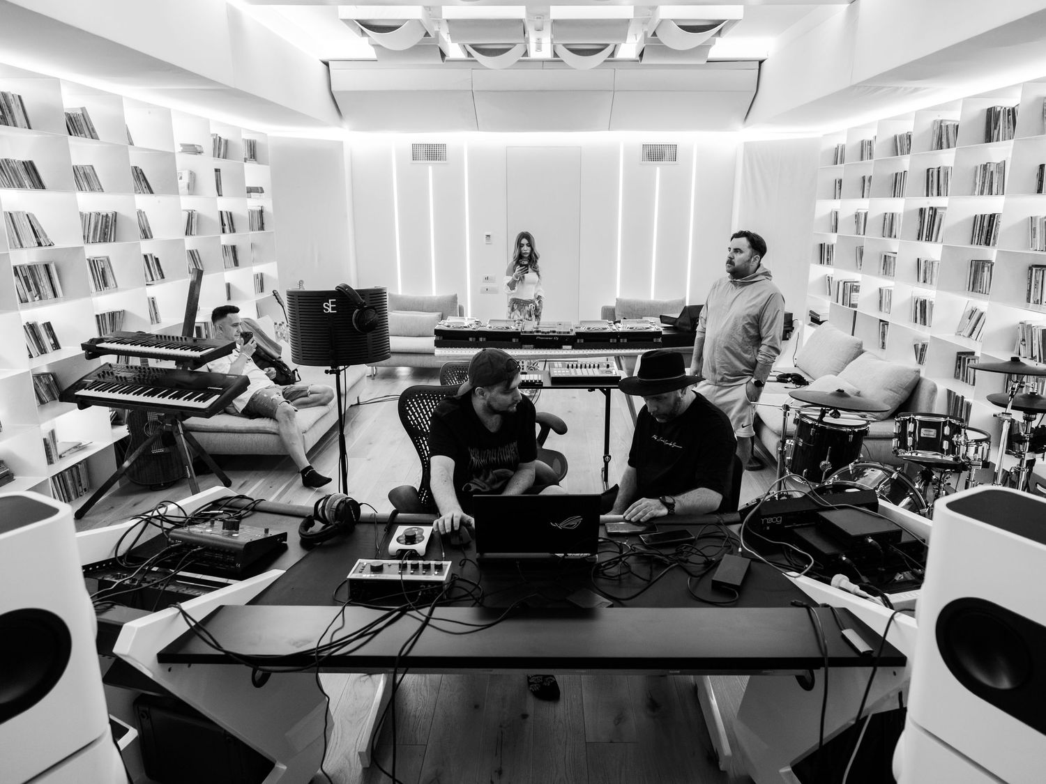 Foto alb-negru cu producatori muzicali lucrand intr-un studio modern de inregistrari