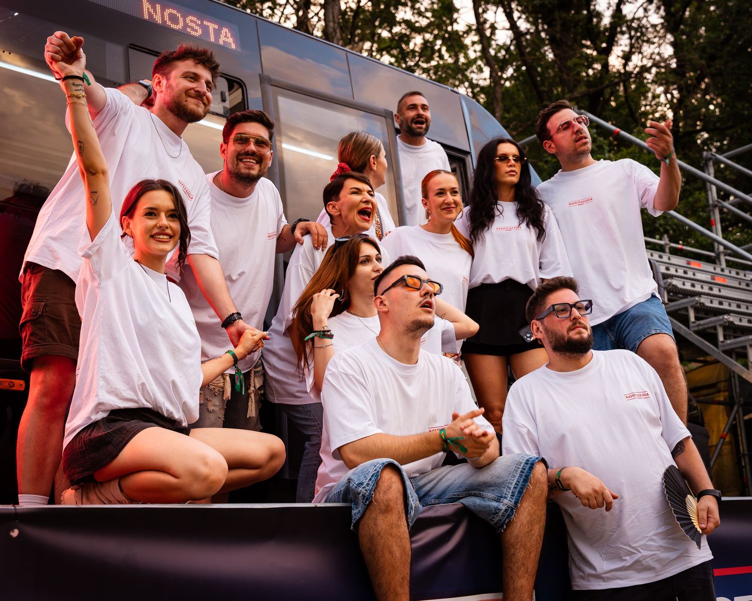 Grup de prieteni in tricouri albe pozand si razand impreuna la un festival in aer liber
