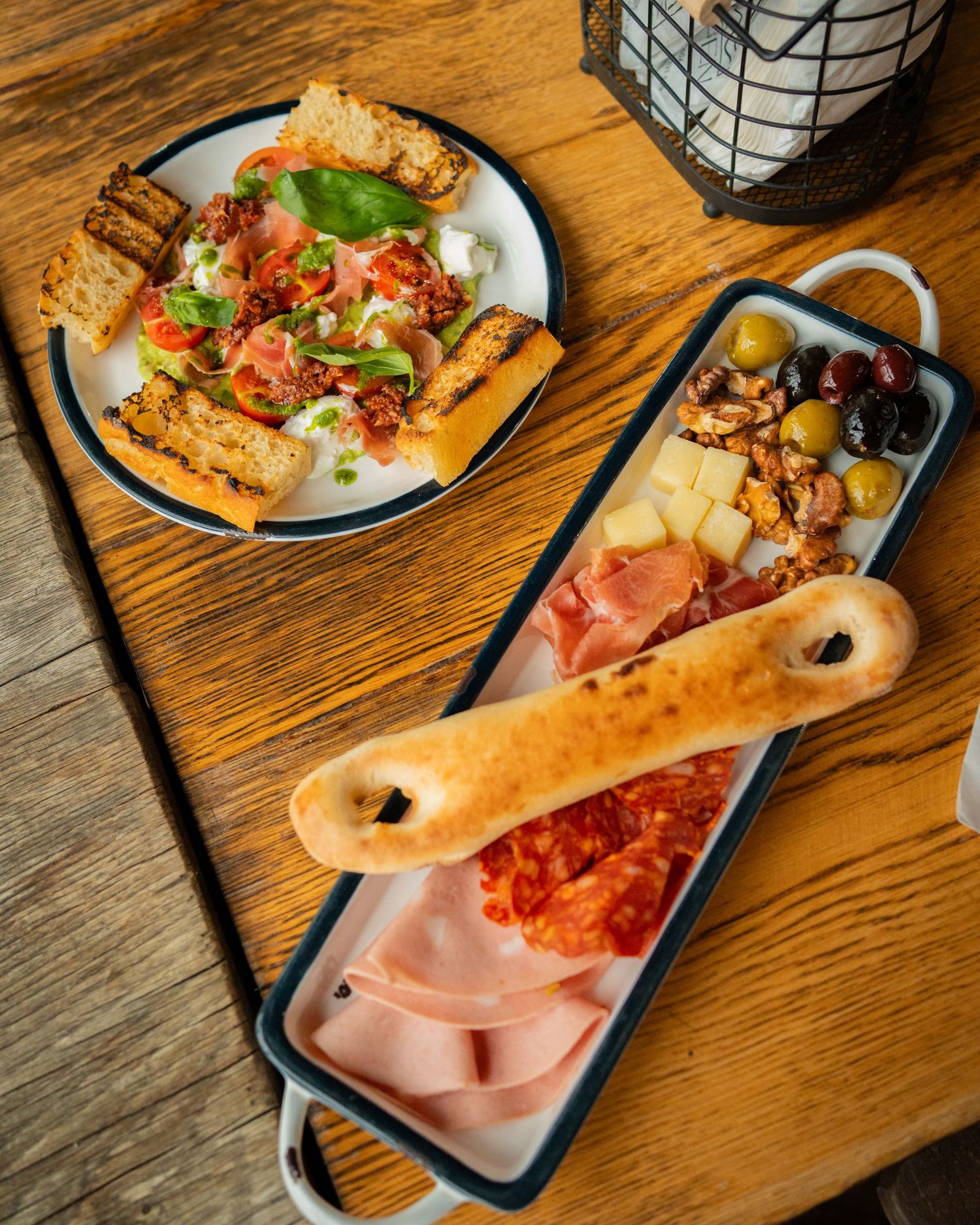 Platou de aperitive italiene cu bruschete si masline pe masa rustica din lemn, fotografie culinara