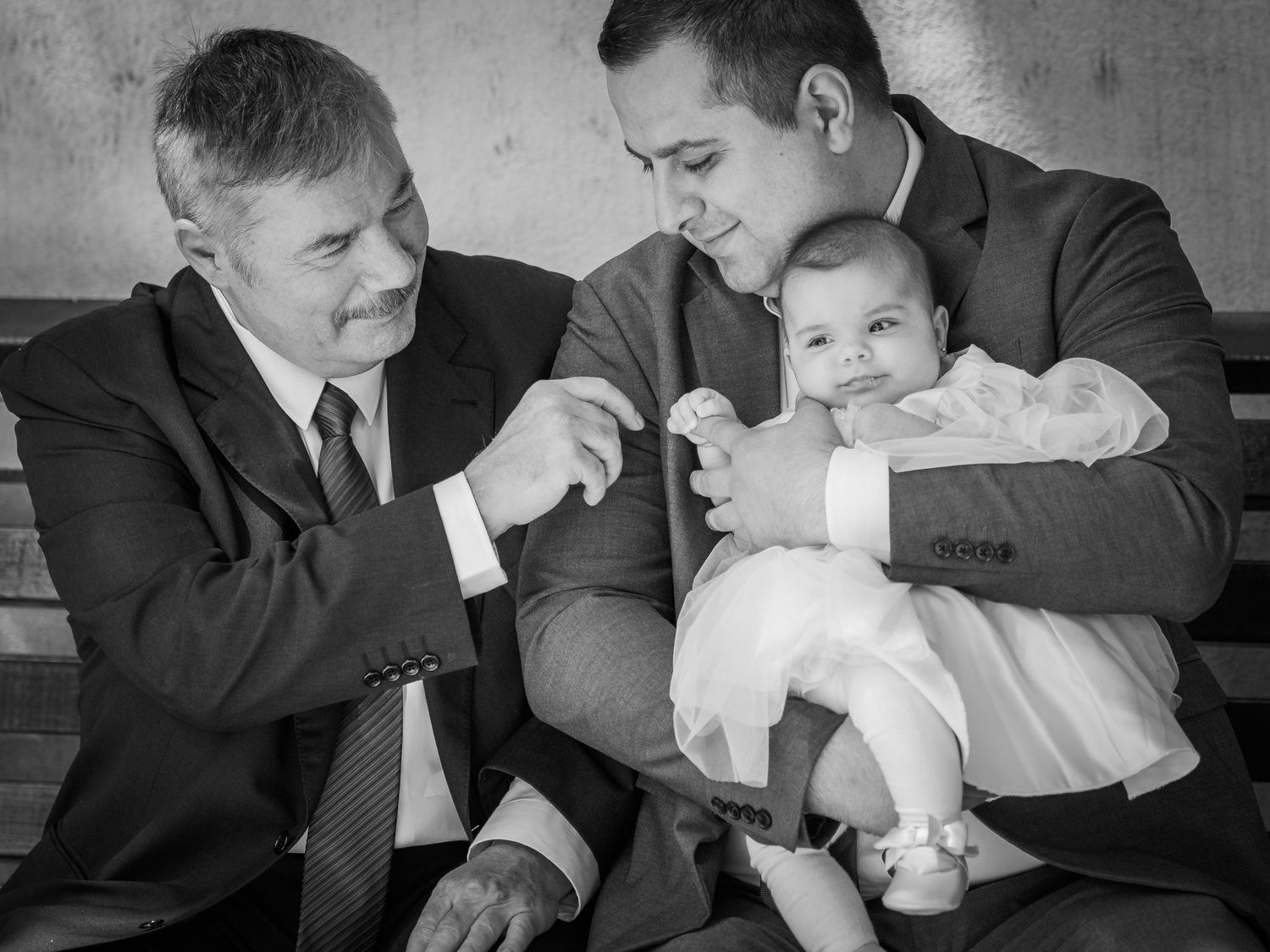 Tatal tinand in brate fiica in timp ce bunicul ei intinde mana sprea ea, portret alb-negru de botez