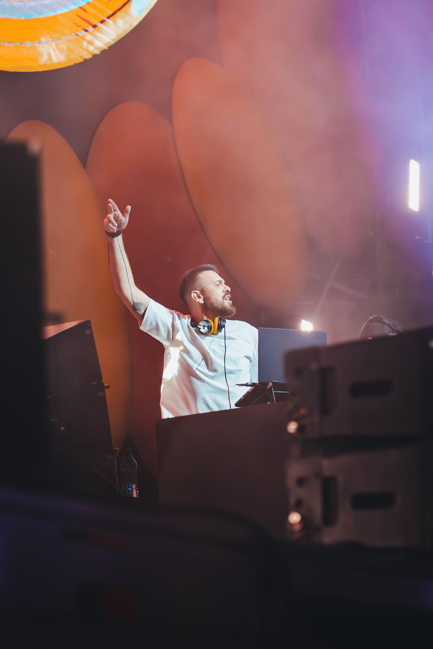 DJ cu casti ridicand mana pe scena la un festival de muzica in aer liber