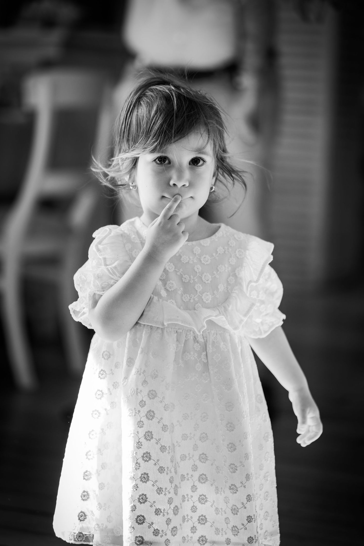 Fetita adorabila in rochie alba tinand degetul la buze, portret alb-negru de nunta