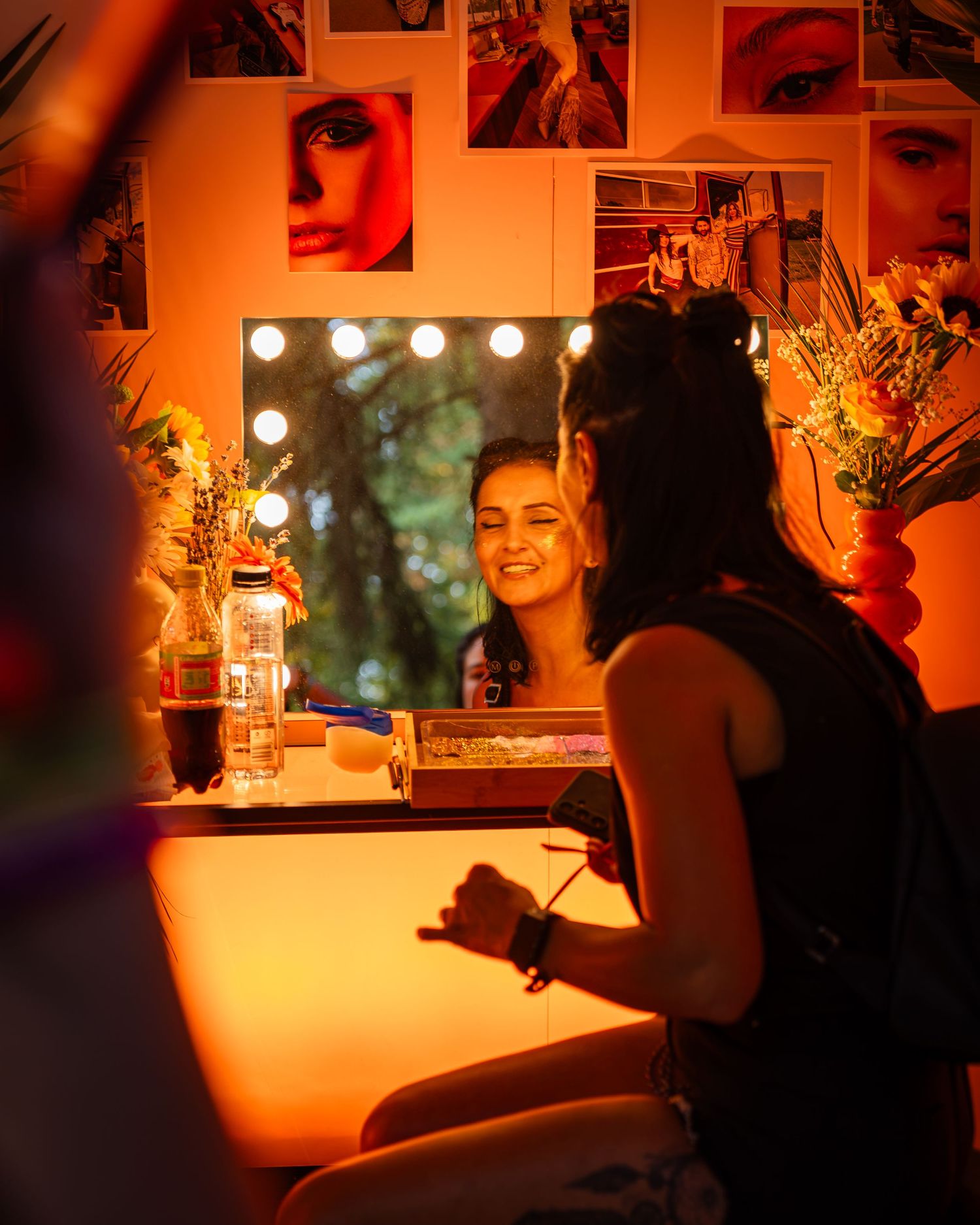 Tanara zambind in fata unei oglinzi de machiaj cu lumini calde la un eveniment