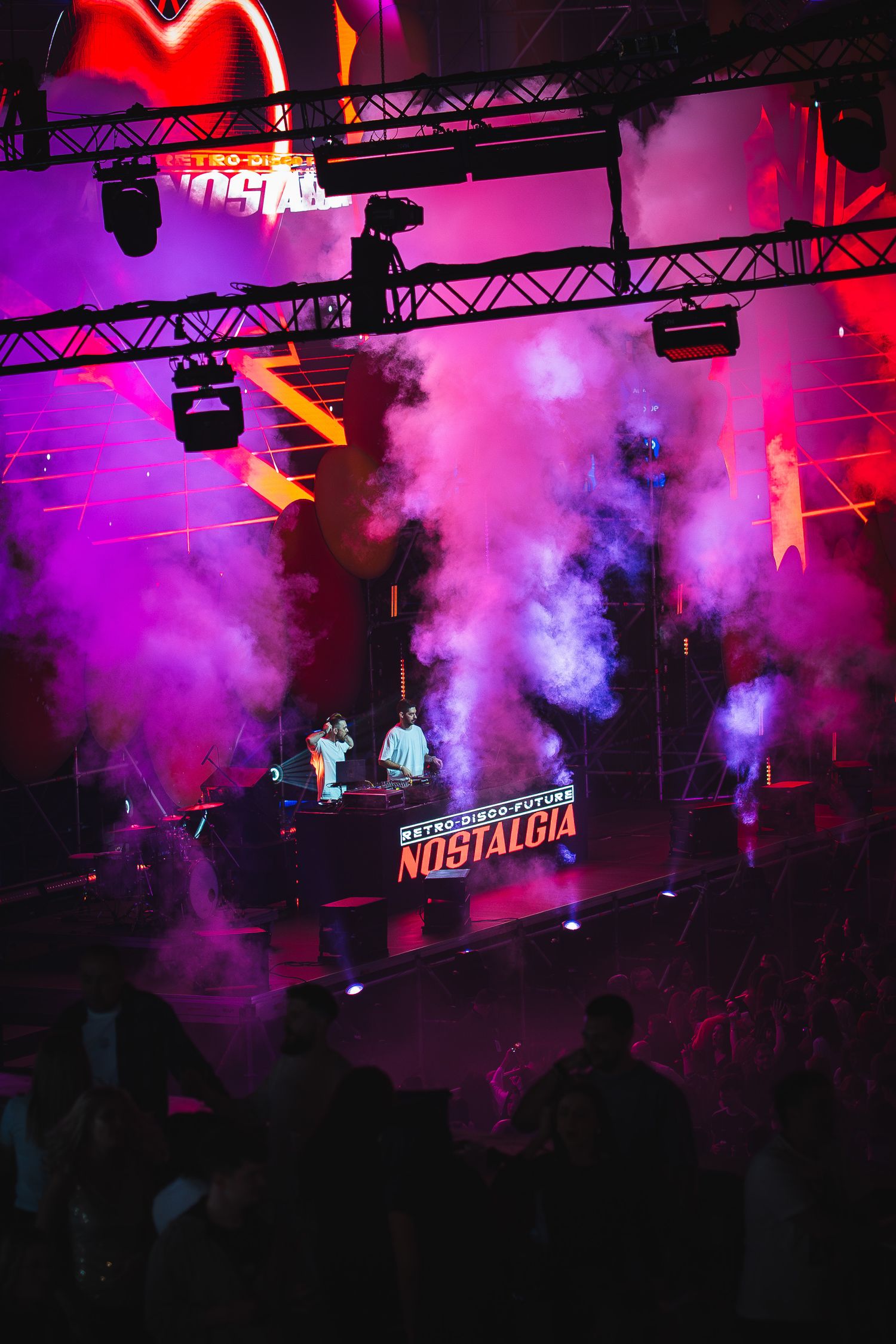 DJ mixand pe scena Nostalgia printre lumini si efecte de fum roz si mov