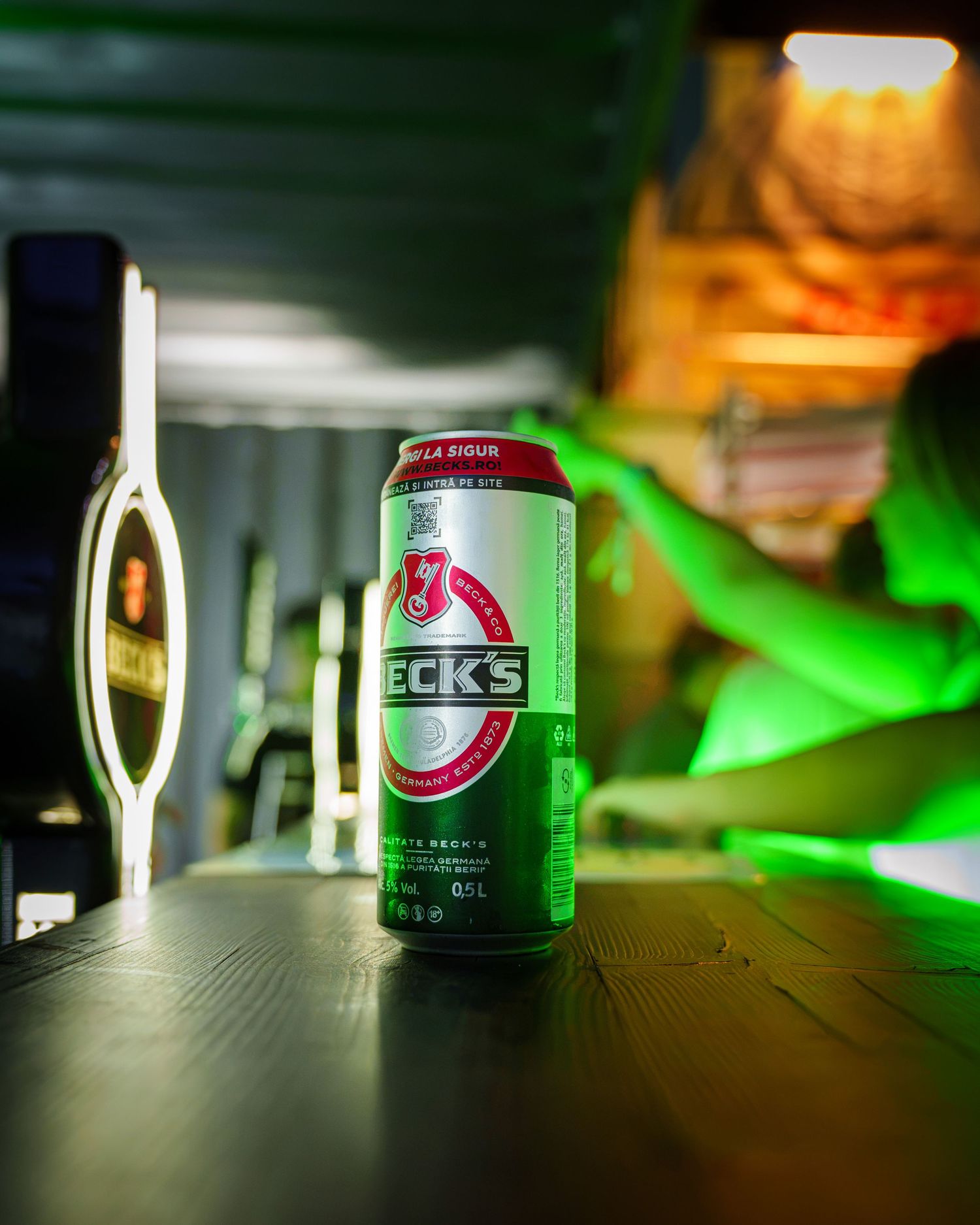 Doza de bere Beck s pe bar cu lumini verzi de neon pe fundal, fotografie de produs