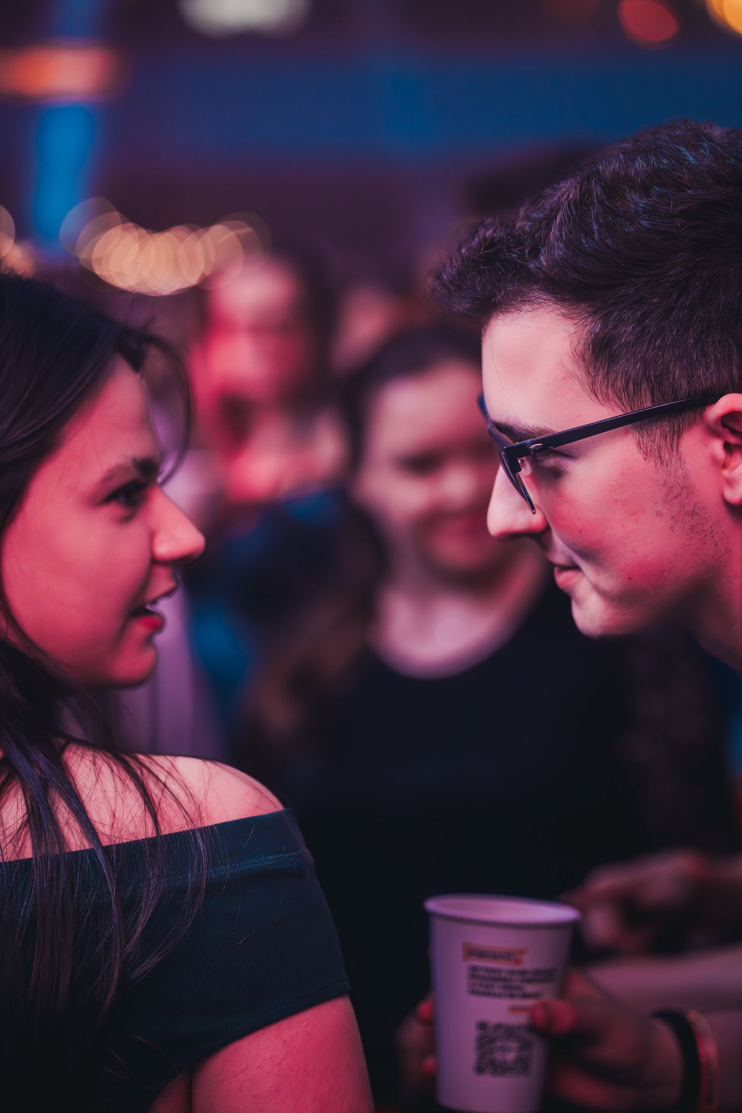 Cuplu tanar impartasind un moment intim in public la o petrecere de club