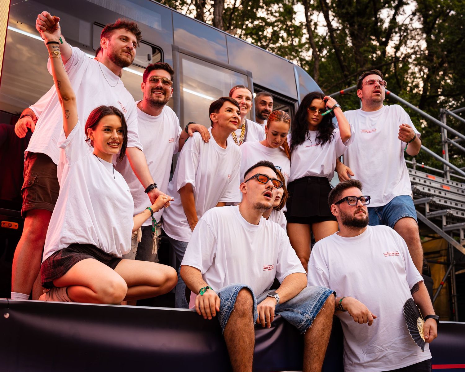 Grup de prieteni in tricouri albe pozand si razand impreuna la un festival in aer liber