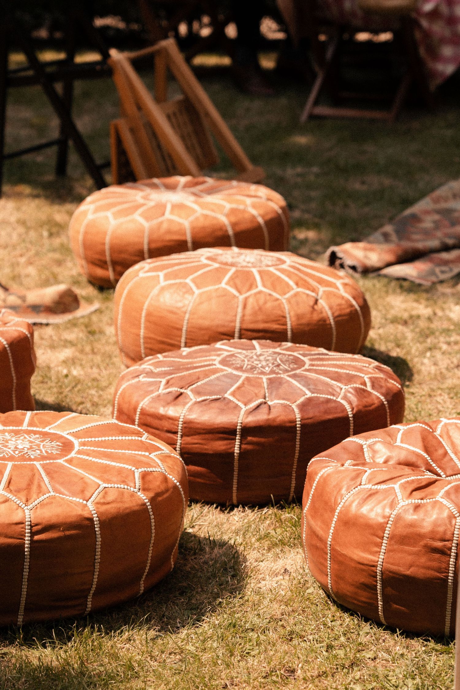 Poufs orange installés sur une pelouse pour l’espace détente d’une réception de mariage en extérieur.