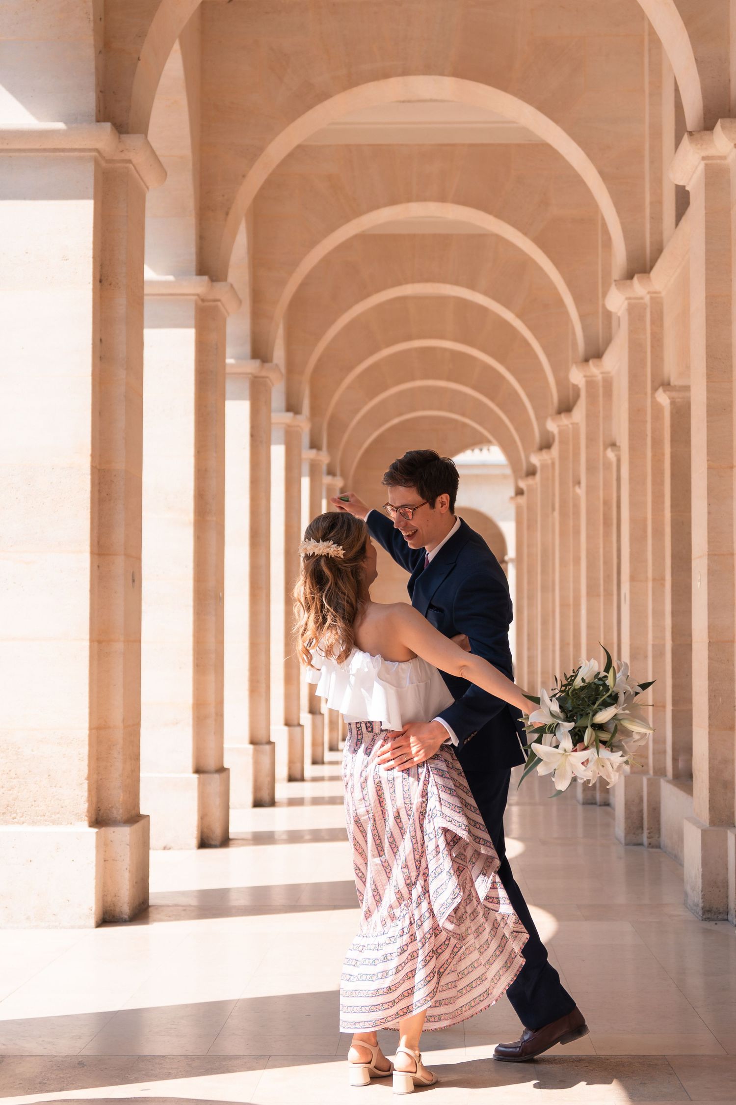 Jeunes mariés dansant sous une colonnade lors de leur séance couple après un mariage civil à Paris.