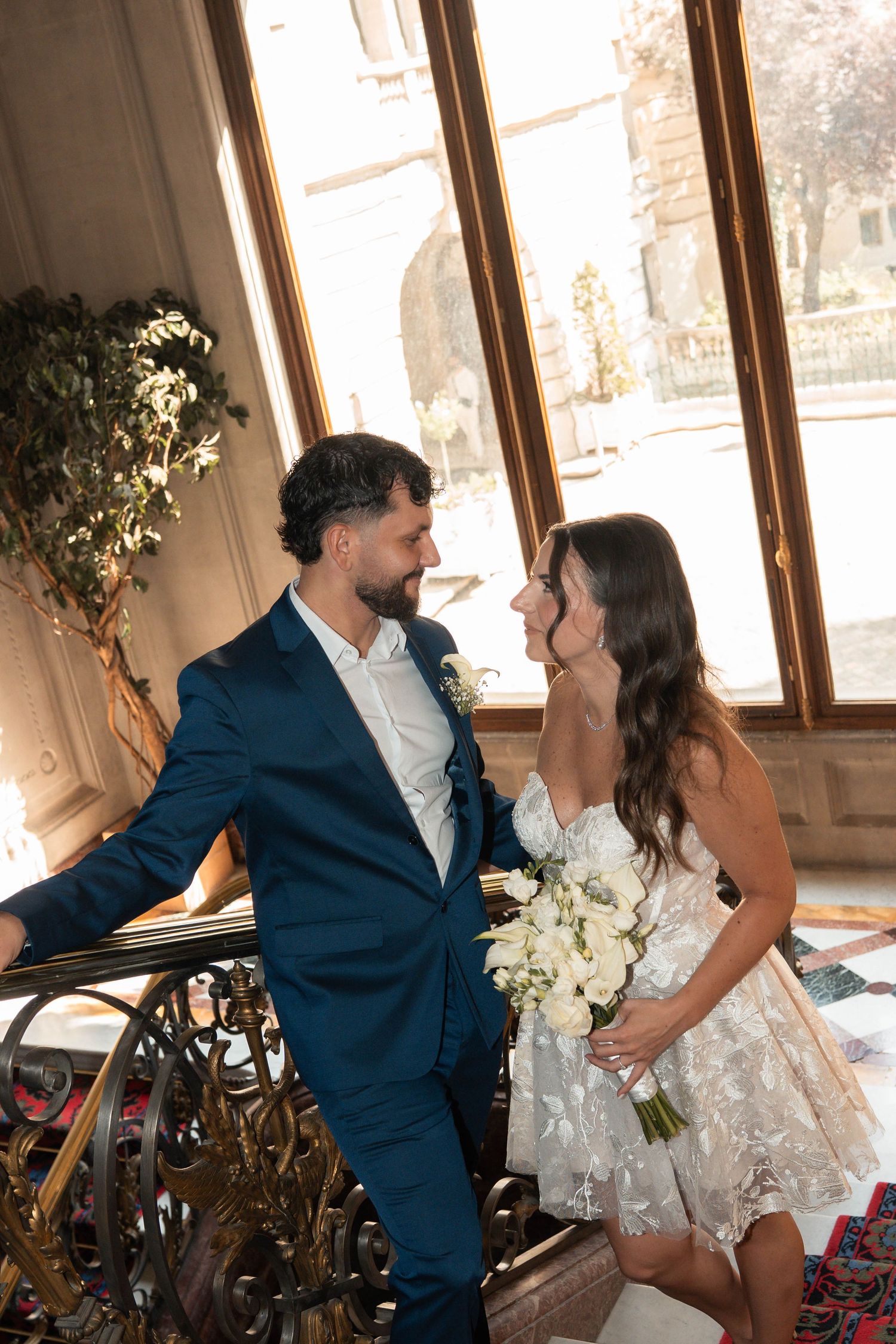 Couple de mariés dans l’intérieur élégant de la mairie du 8e arrondissement de Paris, la mariée tenant un bouquet blanc.