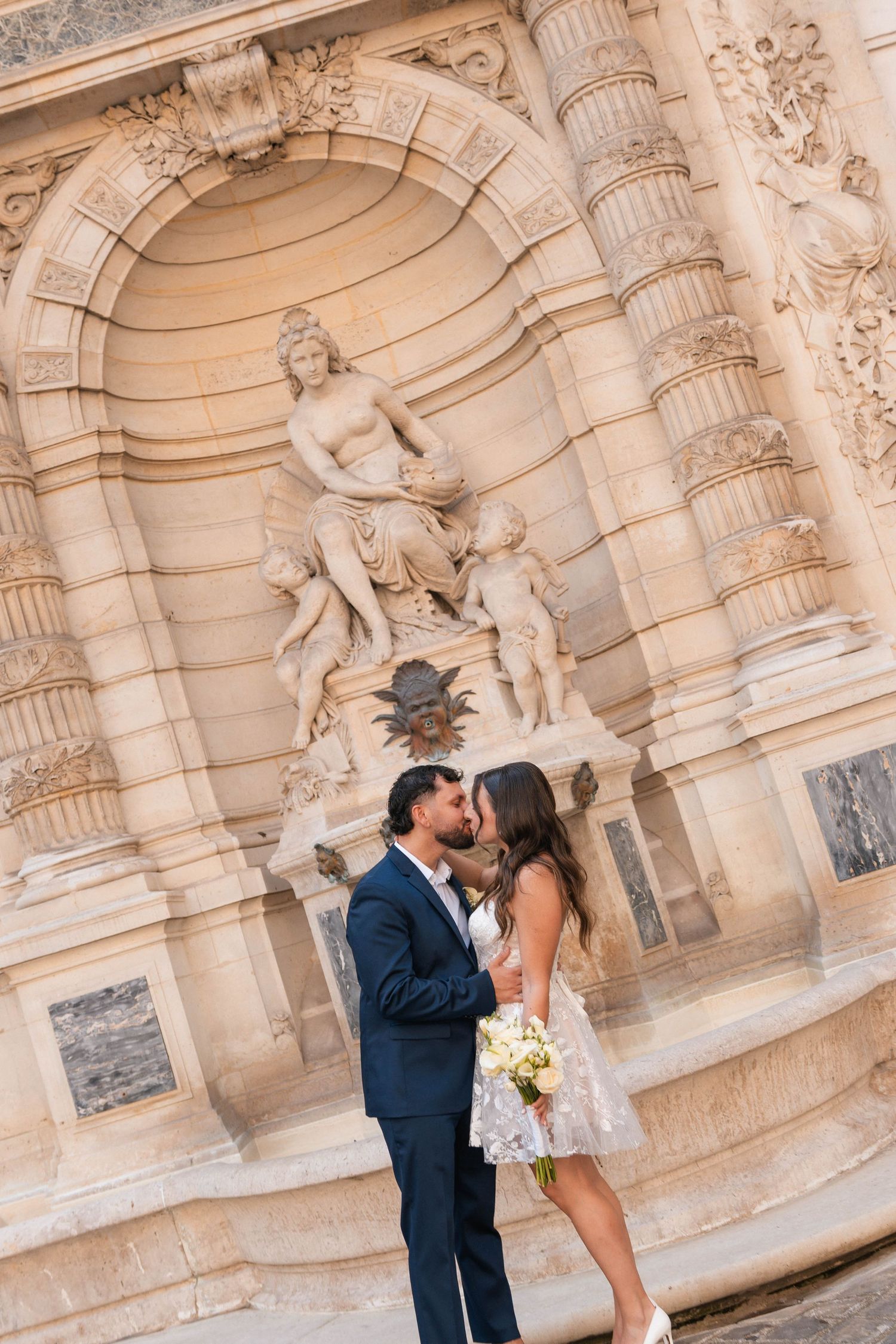Couple de mariés s’embrassant devant la fontaine de la mairie du 8e arrondissement de Paris.