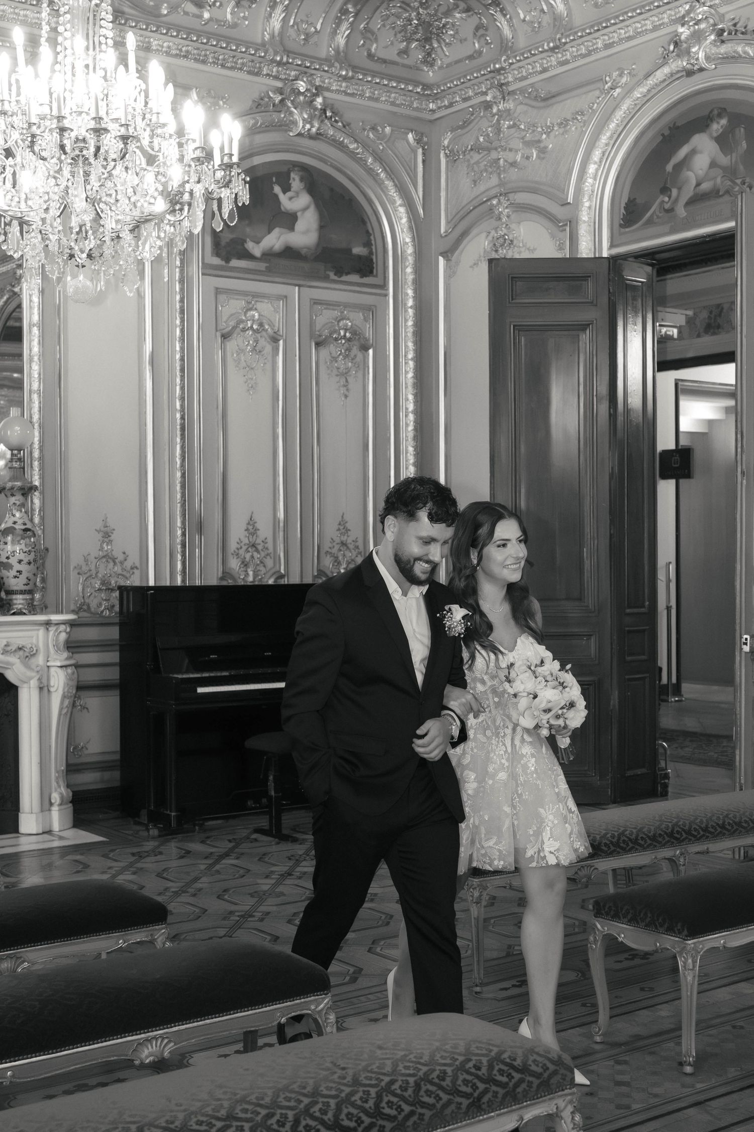 Couple de mariés dans la salle de mariage de la mairie du 8e arrondissement de Paris au décor sculpté, photographié en noir et blanc.