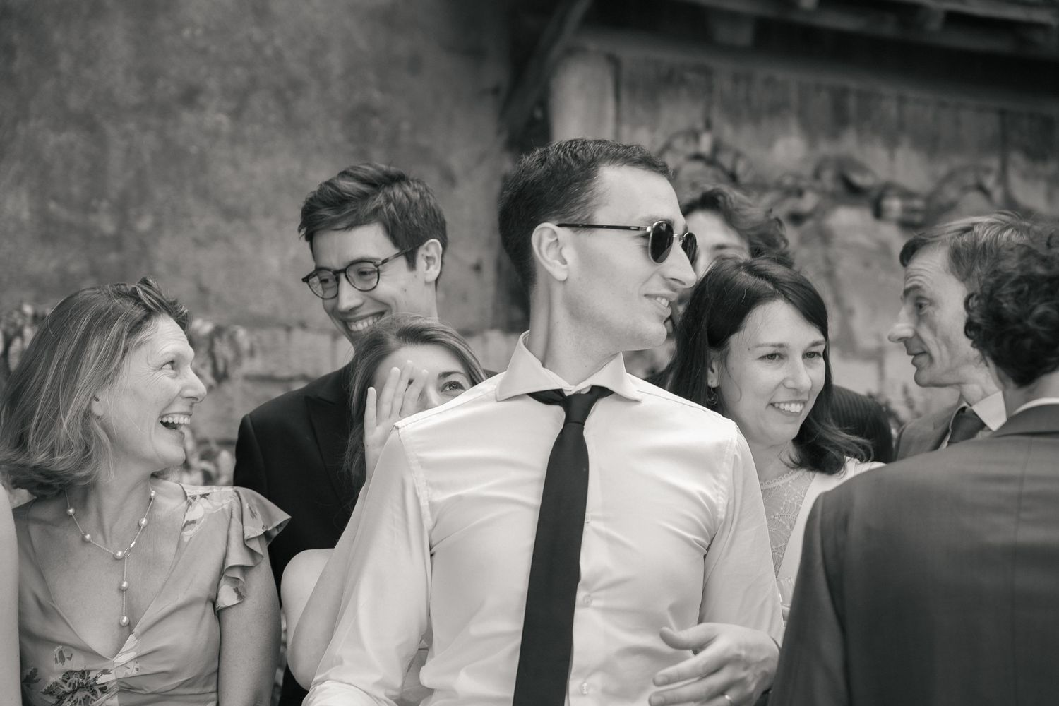 Marié dansant au milieu de ses proches pendant une réception de mariage, photographié en noir et blanc.