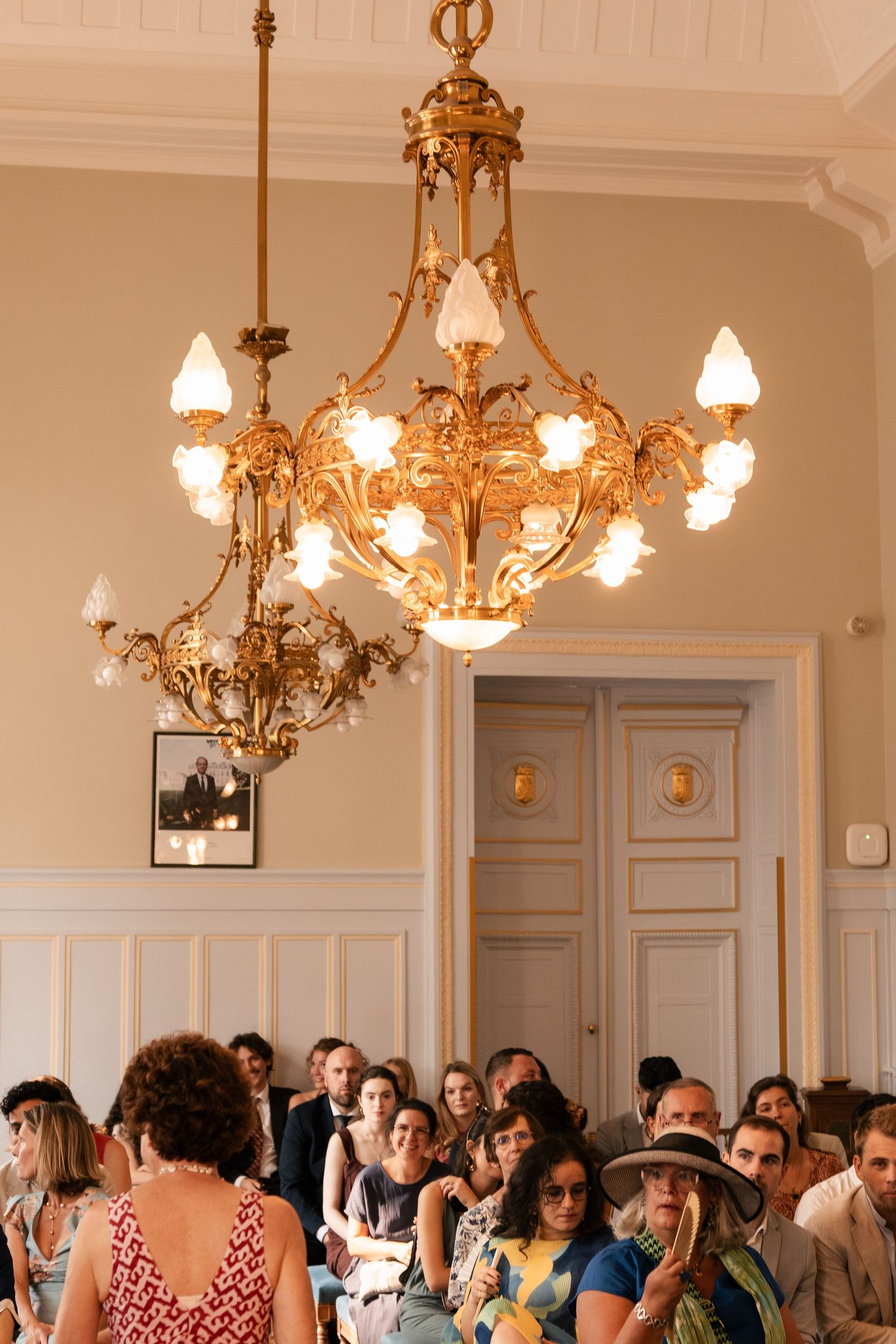 Invités réunis sous un lustre ancien dans la salle de cérémonie d’une mairie parisienne.