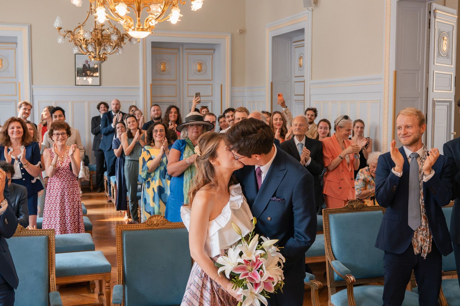 Baiser des mariés sous les applaudissements de leurs invités lors de leur cérémonie civile à Paris.