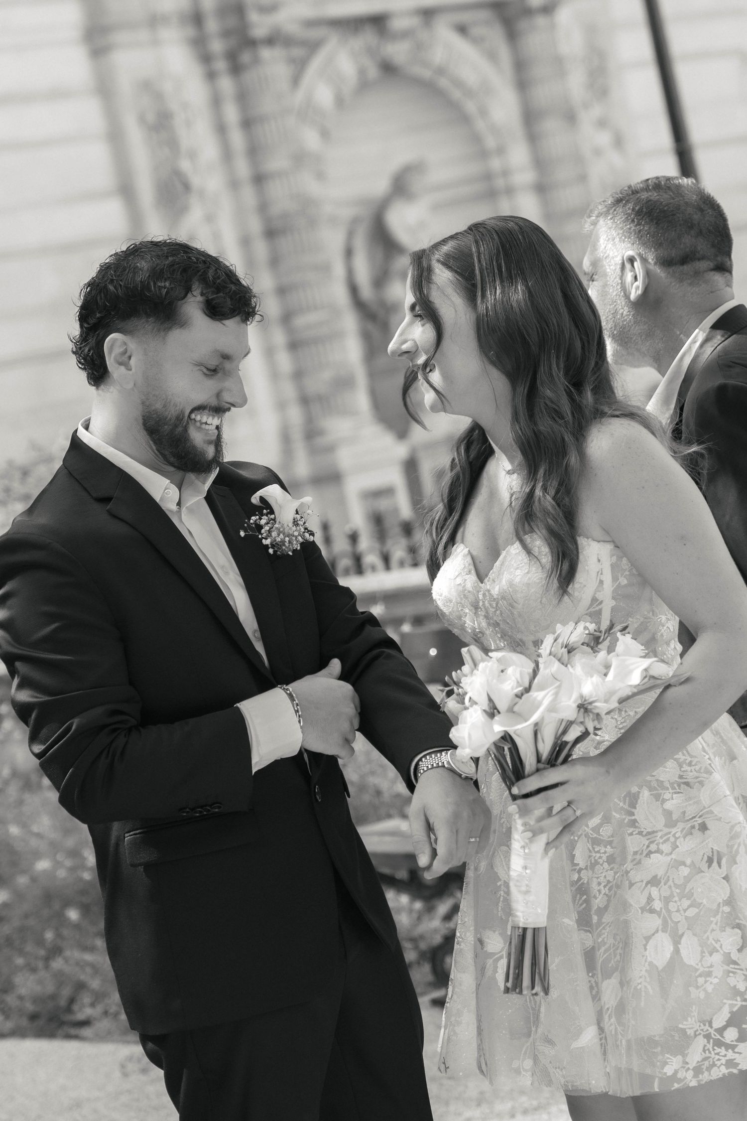 Mariés échangeant un regard complice, la mariée tenant son bouquet, photographiés en noir et blanc.