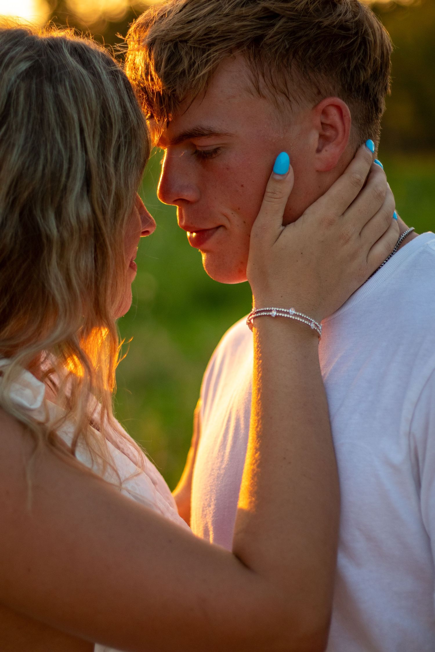 Young woman tenderly holding mans face in warm golden sunset light.