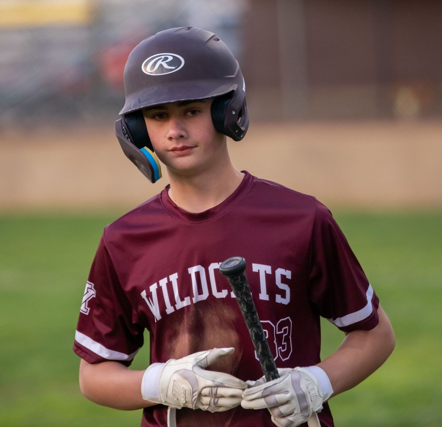 Young Wildcats baseball player in maroon uniform holding bat at home plate.